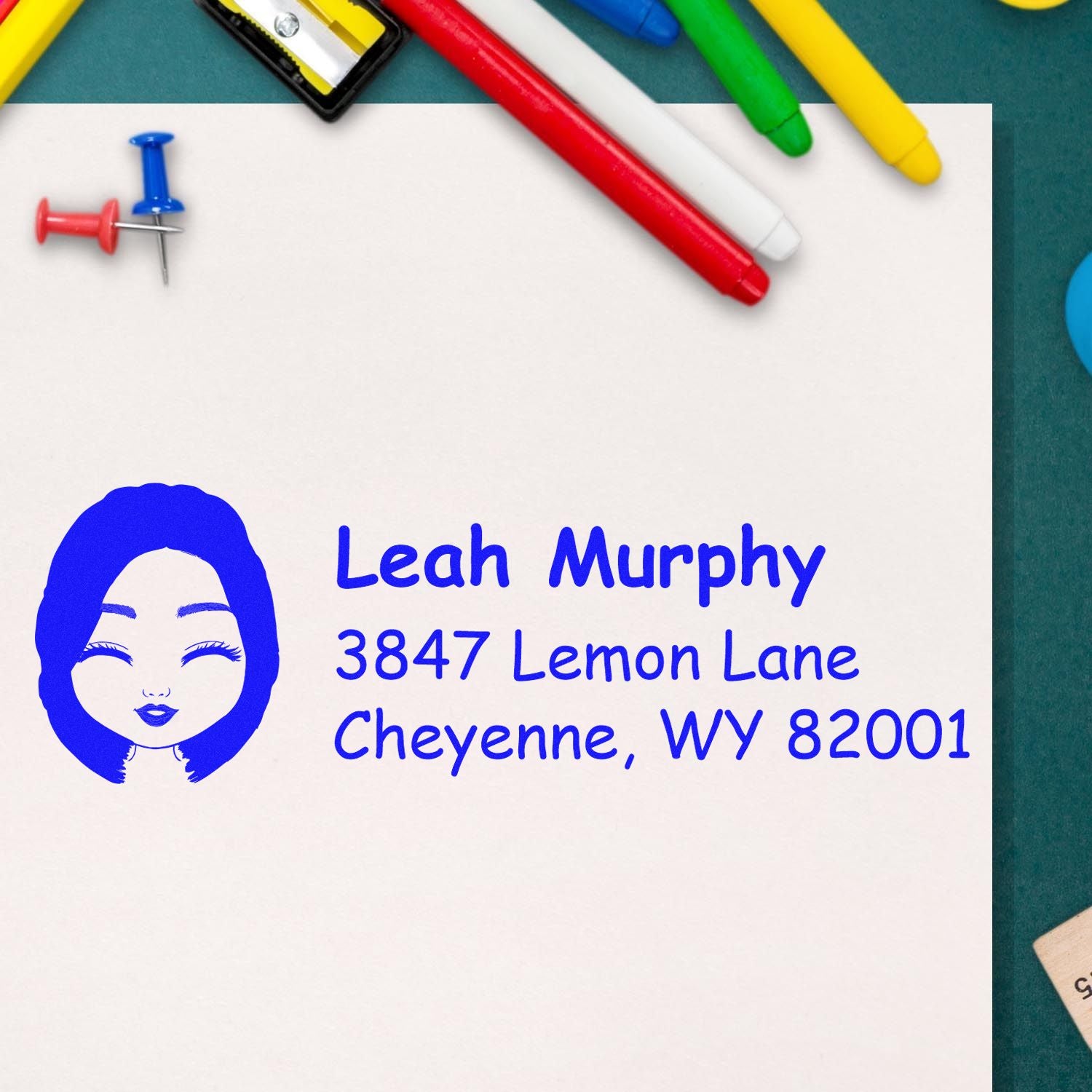 Custom return address rubber stamp with illustrated face logo, Leah Murphy, 3847 Lemon Lane, Cheyenne, WY 82001.
