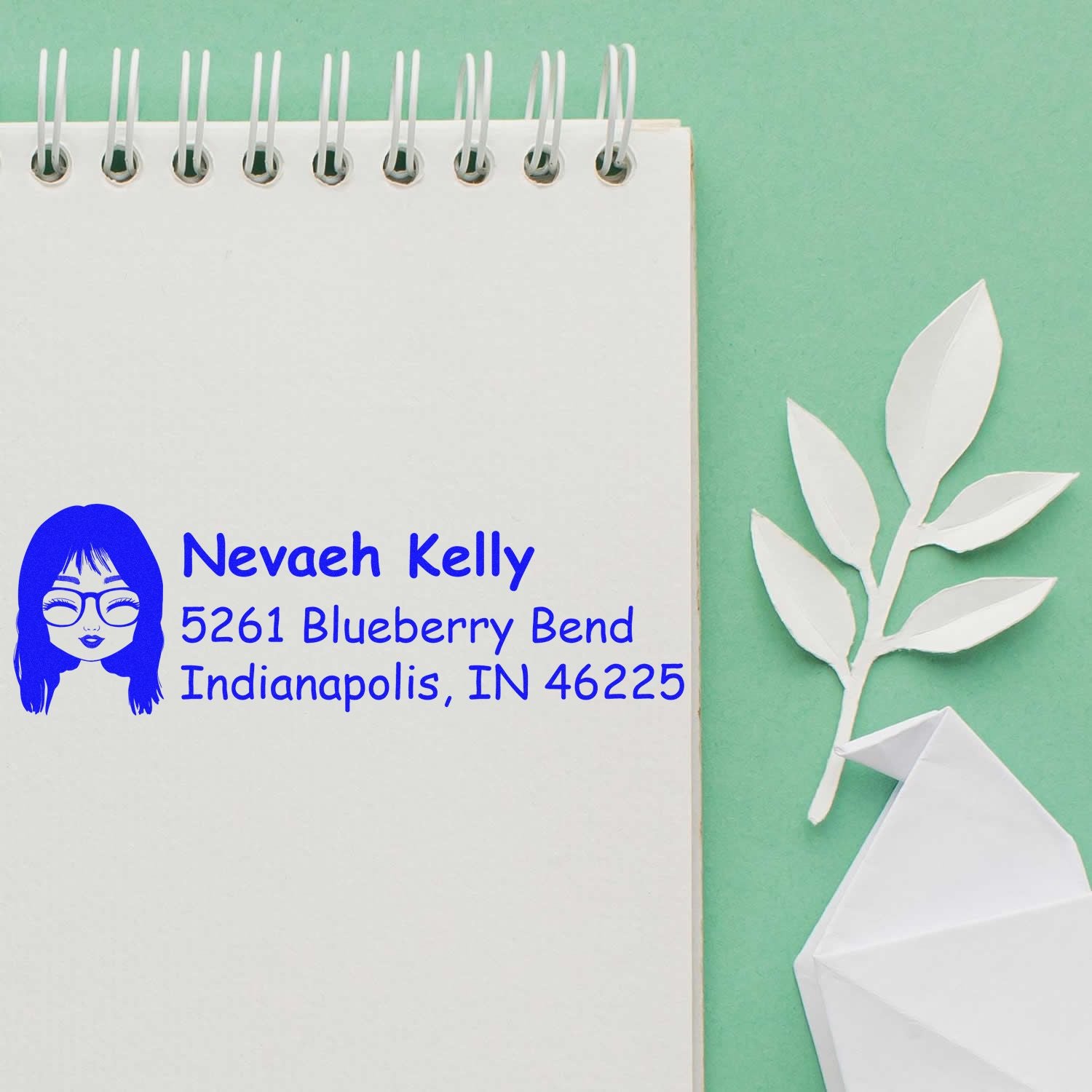 Custom return address rubber stamp on notebook page, featuring avatar icon, Nevaeh Kelly, and Indianapolis, IN address.