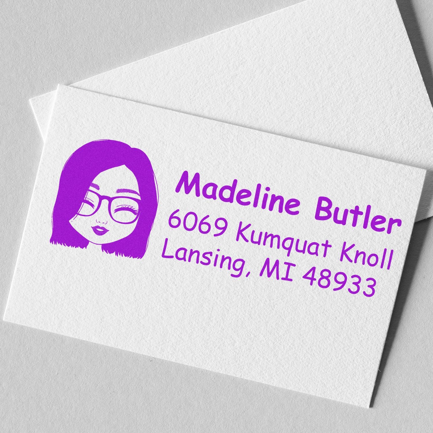 Custom rubber address stamp with purple avatar design and Madeline Butler return address, Lansing, MI 48933.