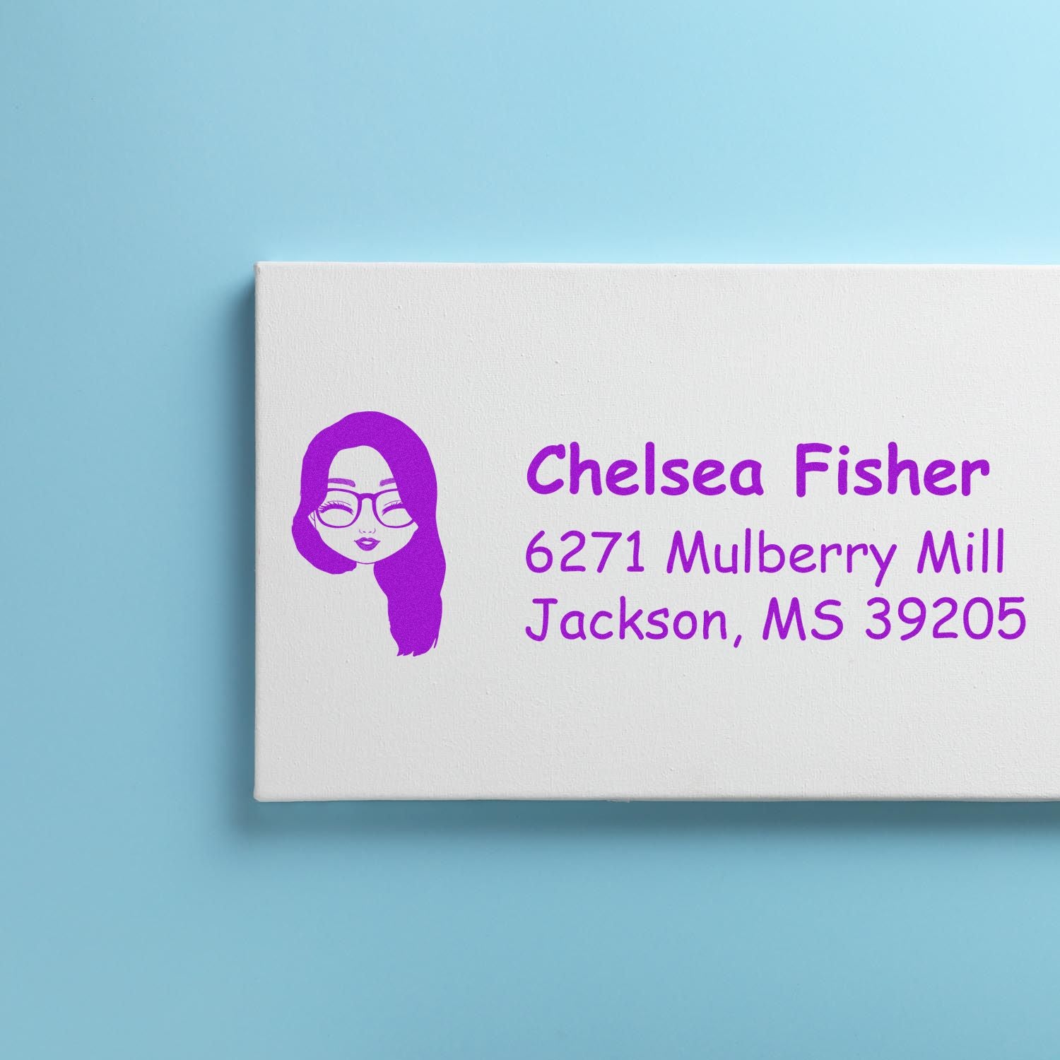 Personalized return address rubber stamp with purple avatar logo, name, and mailing address on a white stamp block.