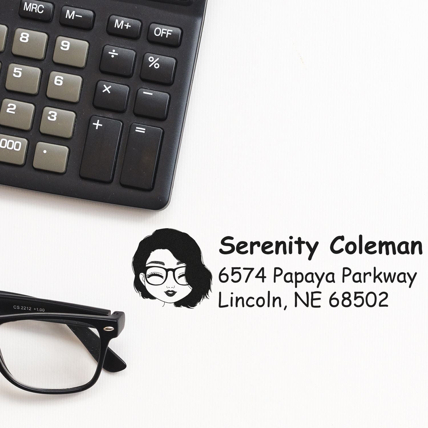 Custom return address rubber stamp with name, address, and avatar beside calculator and glasses.