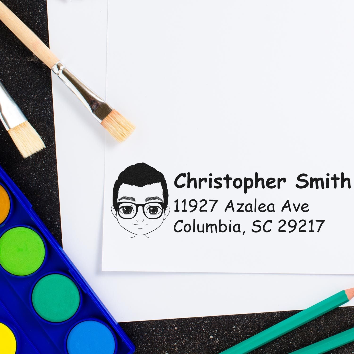 Personalized custom address rubber stamp with cartoon portrait, name, and mailing address on paper.