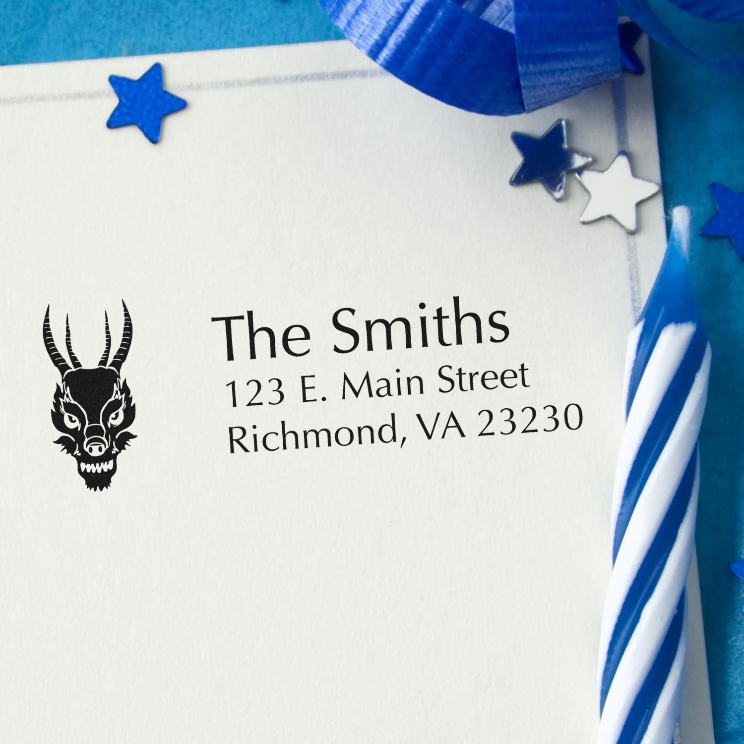 Personalized rubber stamp return address with dragon logo for The Smiths on a white envelope with blue ribbon and stars.