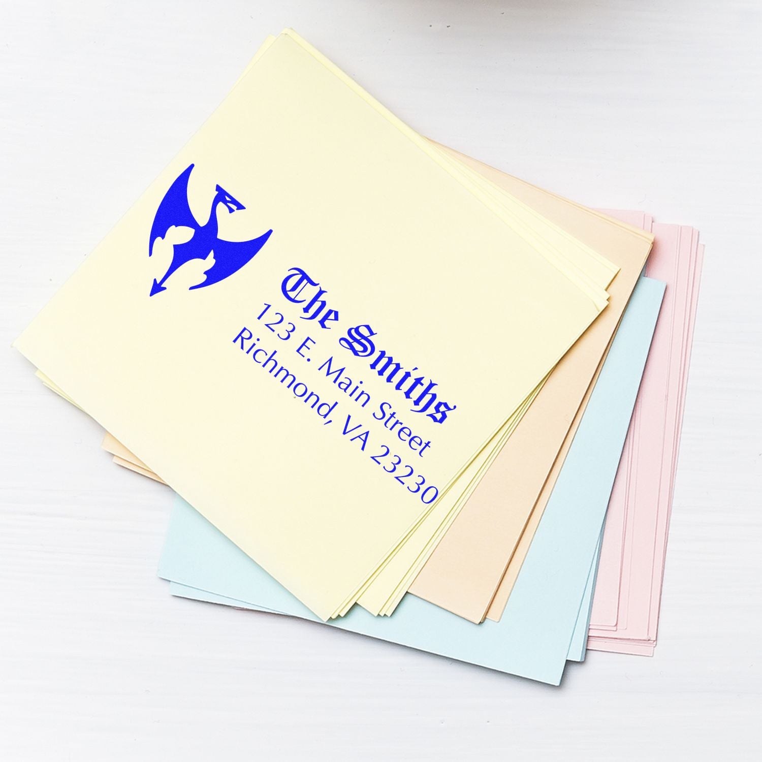 Custom return address rubber stamp for personalized stationery with blue name, logo, and mailing address design.