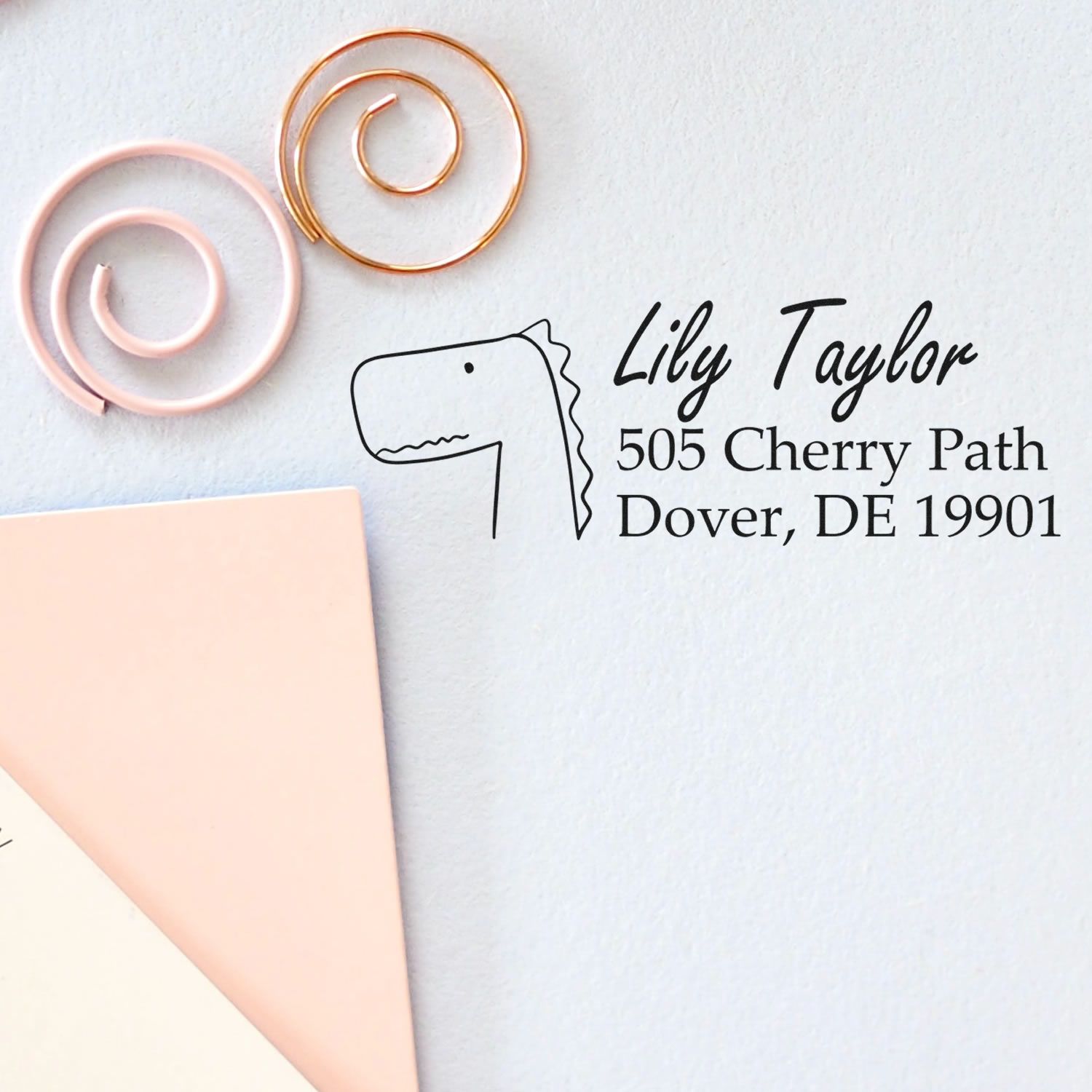Custom rubber return address stamp with dinosaur design for personalized envelope addressing and mailing labels.