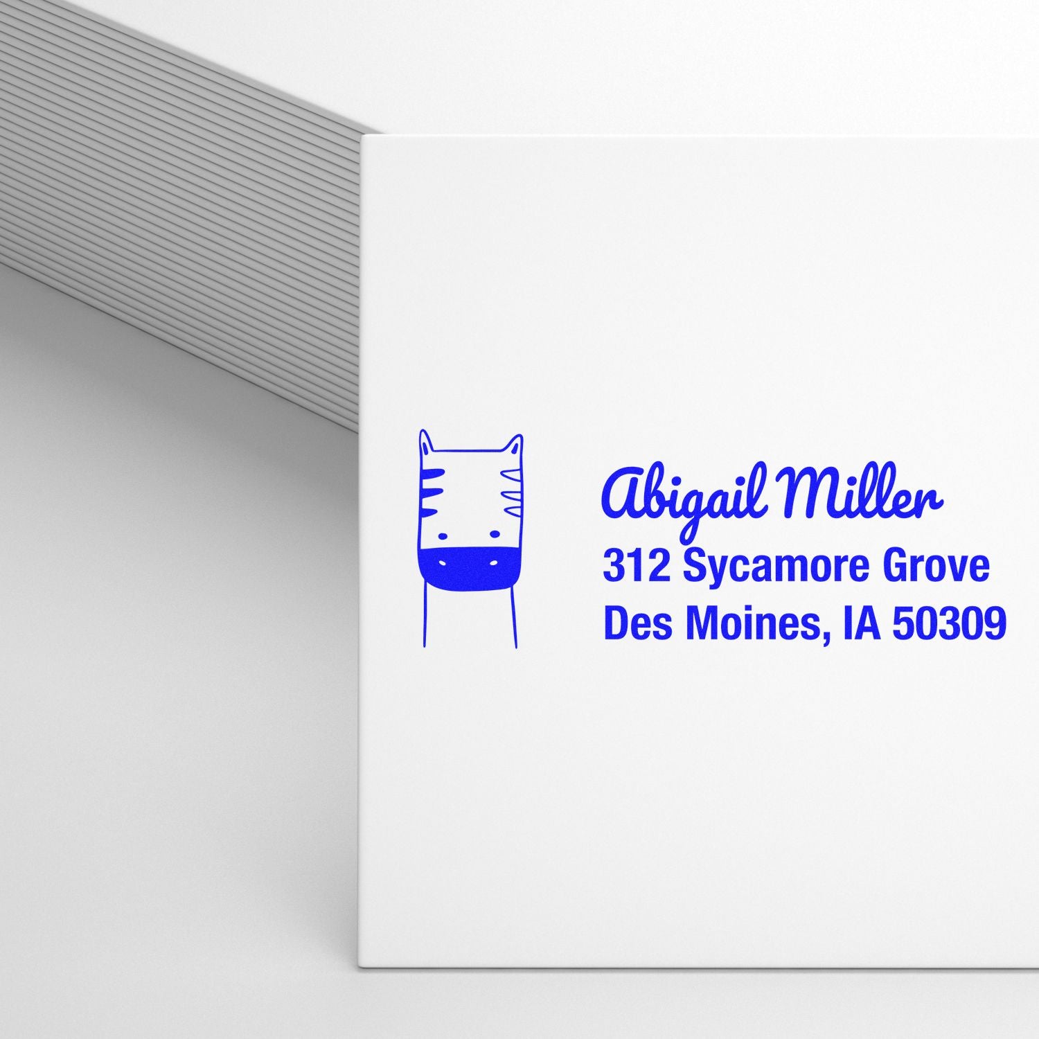 Custom blue return address rubber stamp with cat icon for Abigail Miller, 312 Sycamore Grove, Des Moines, IA 50309
