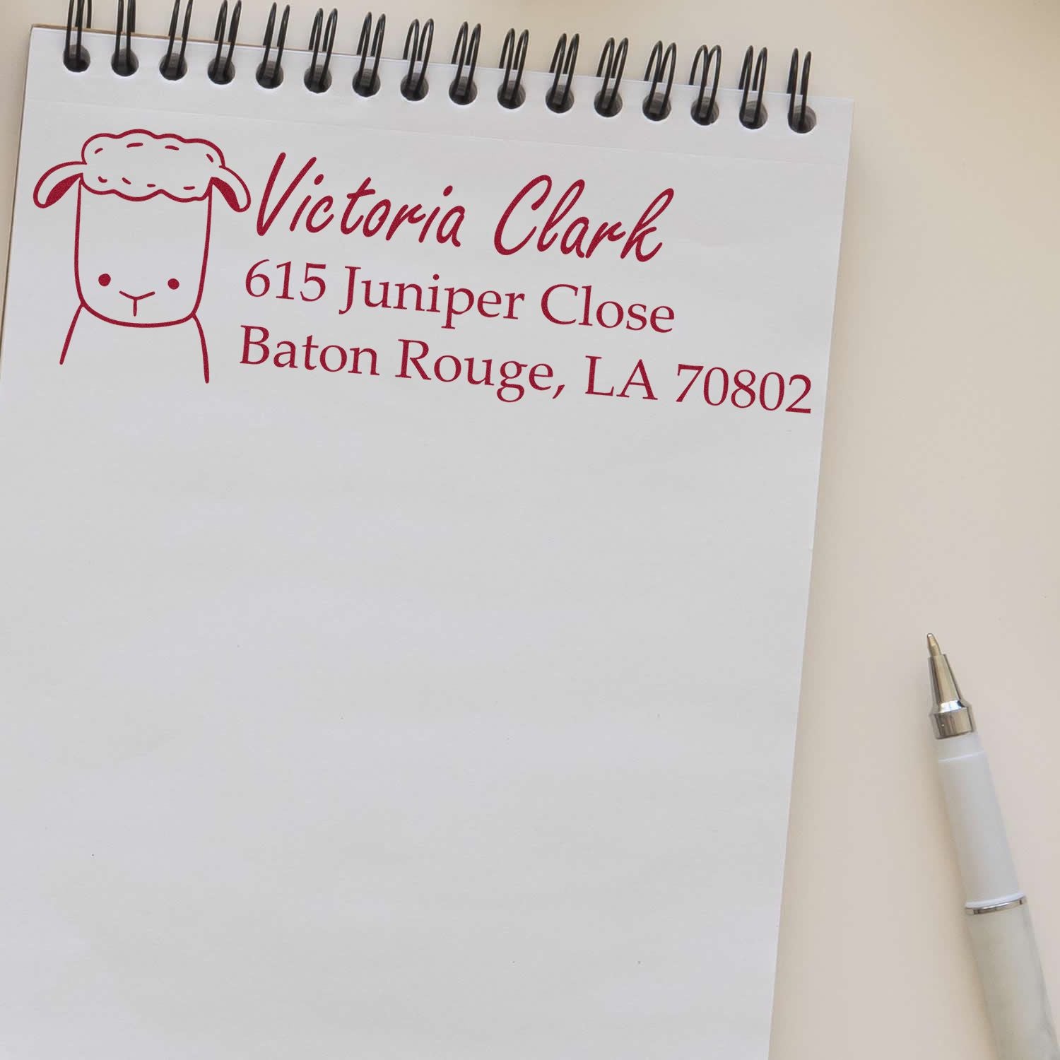 Custom address rubber stamp with sheep icon, showing Victoria Clark and Baton Rouge, LA mailing details on a notepad.