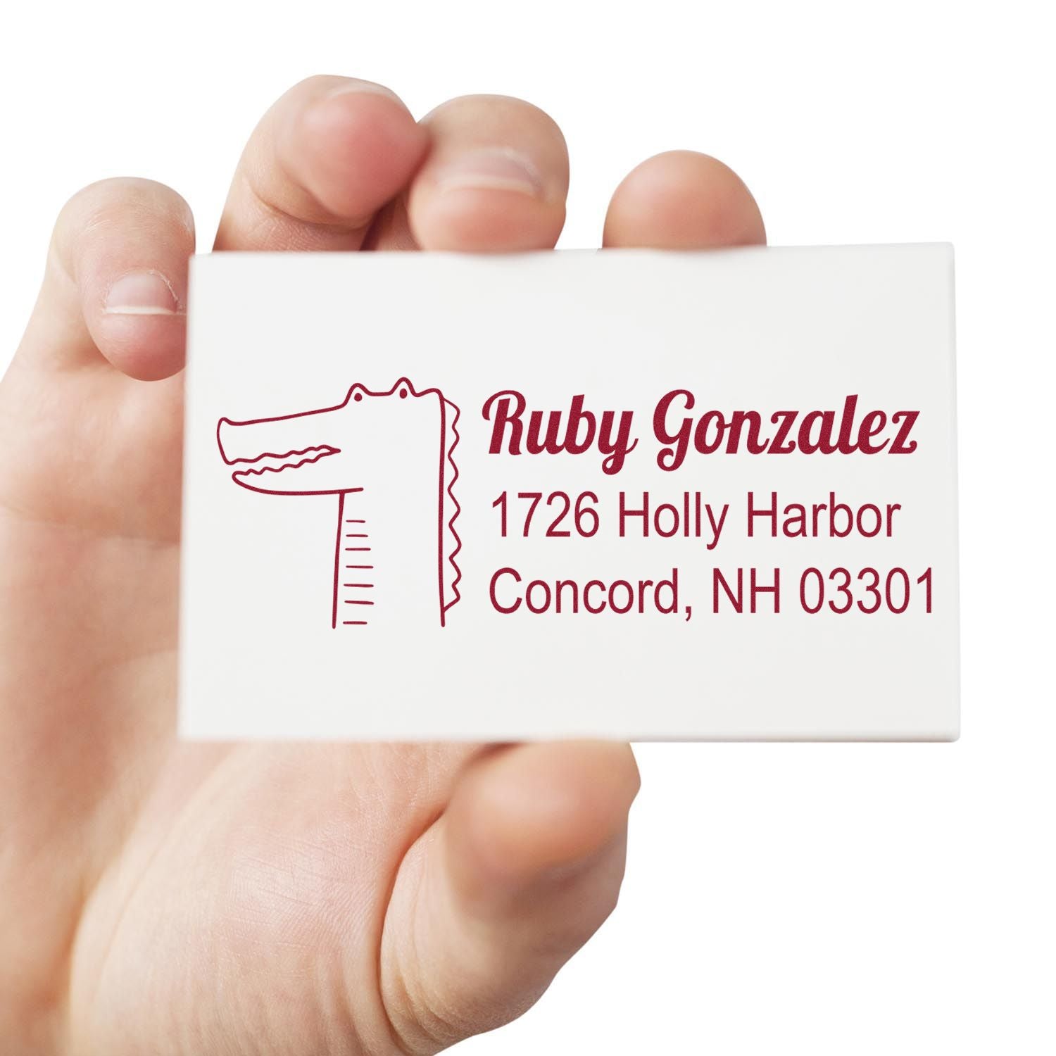 Hand holding custom return address rubber stamp with crocodile design, personalized name and address for mailing labels.