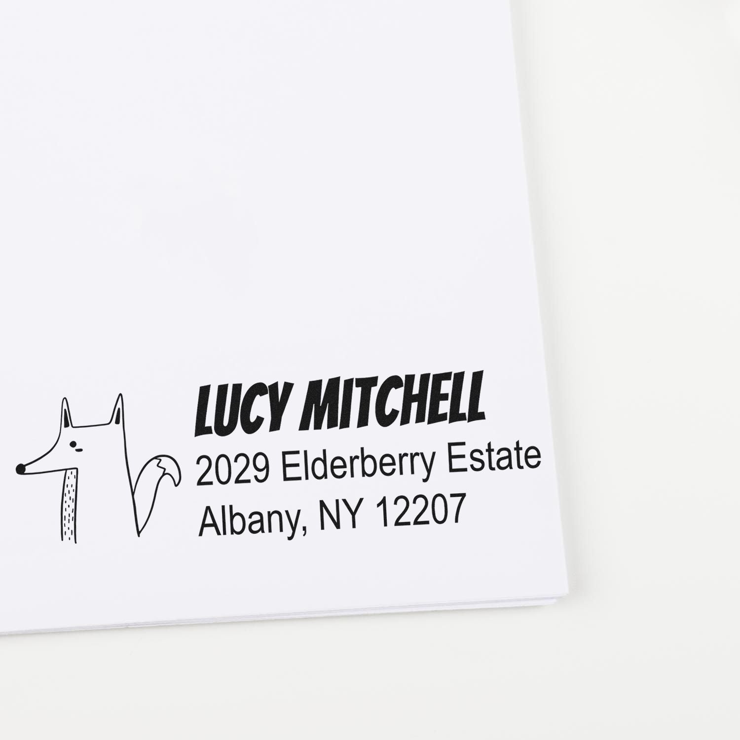 Custom rubber address stamp with dog illustration, featuring Lucy Mitchell return address for mailing envelopes.