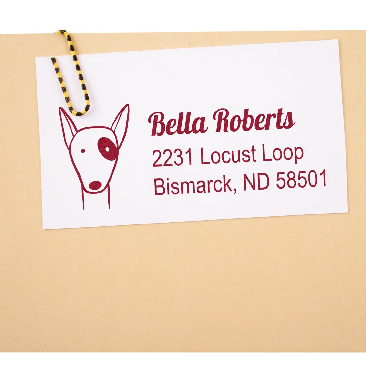 Custom rubber address stamp with dog logo, featuring Bella Roberts return address in Bismarck, ND.