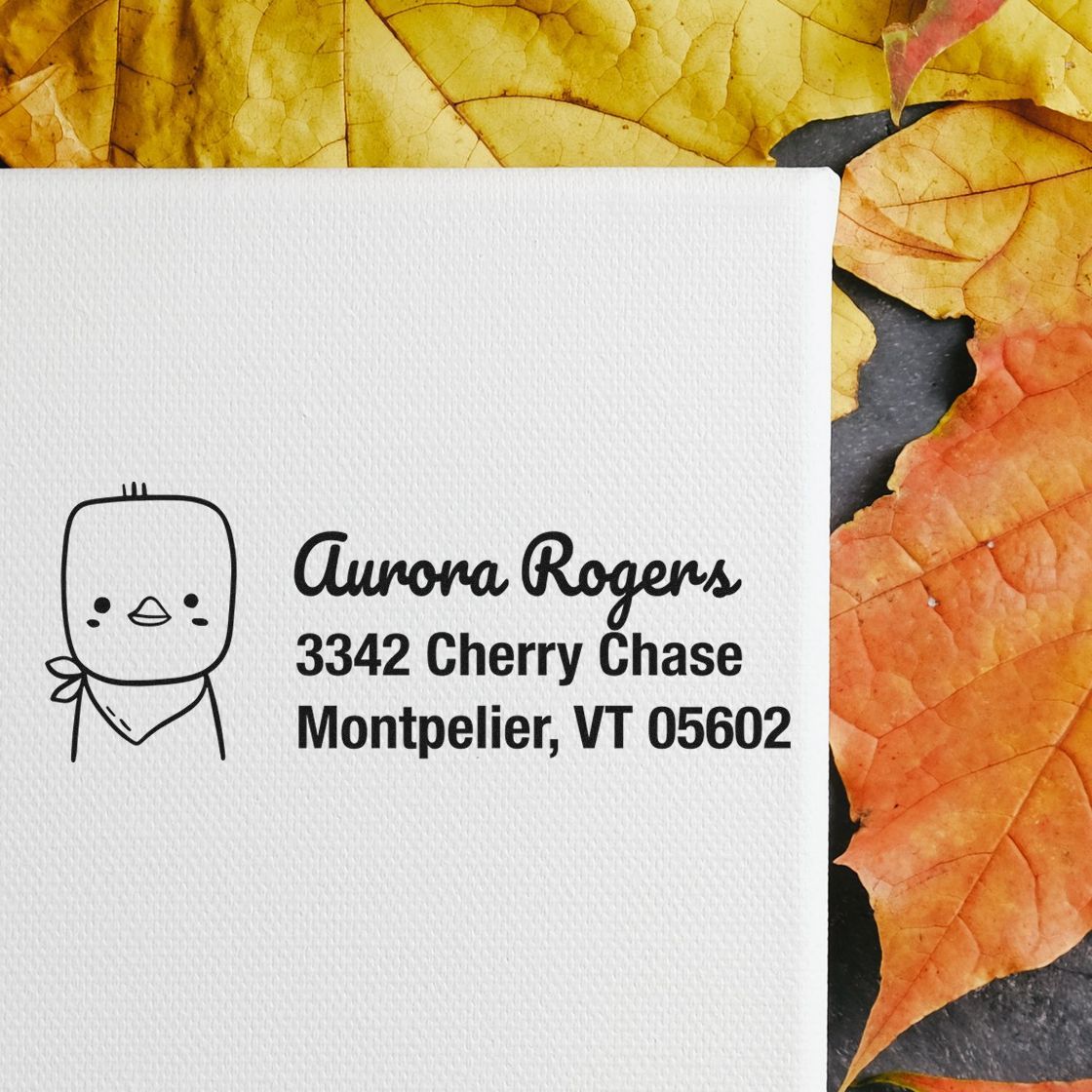 Custom rubber return address stamp with cute bird icon for Aurora Rogers, Montpelier VT, on white textured paper.
