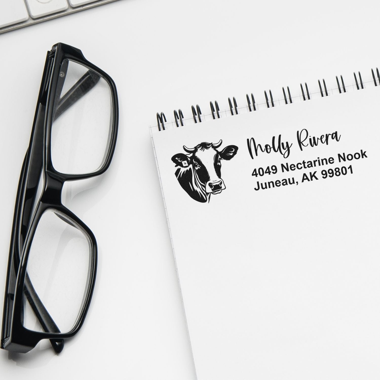 Custom cow address rubber stamp example on notebook, ideal for personalized mailing labels and business stationery.
