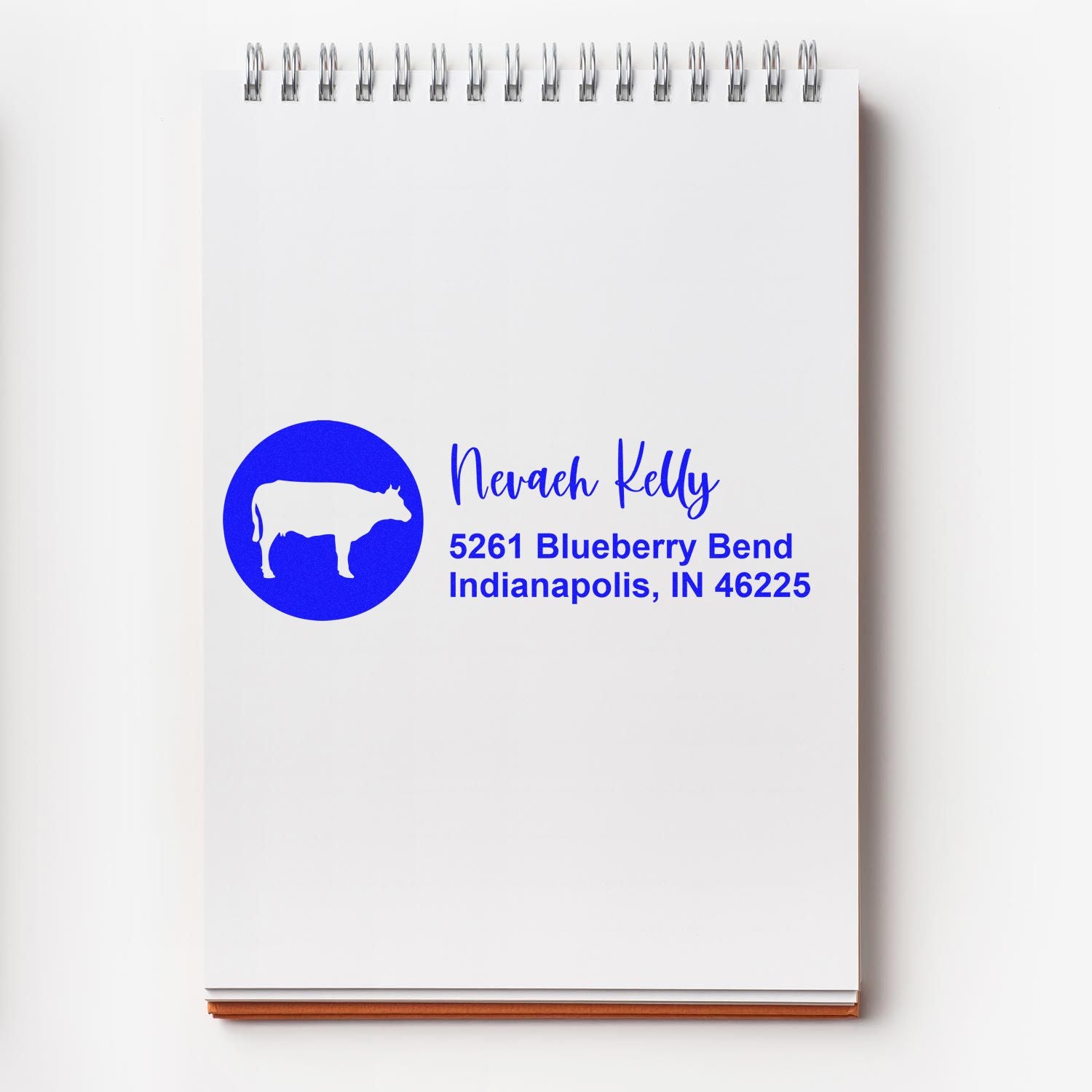 Custom rubber address stamp with cow logo for Nevaeh Kelly, 5261 Blueberry Bend, Indianapolis, IN 46225.