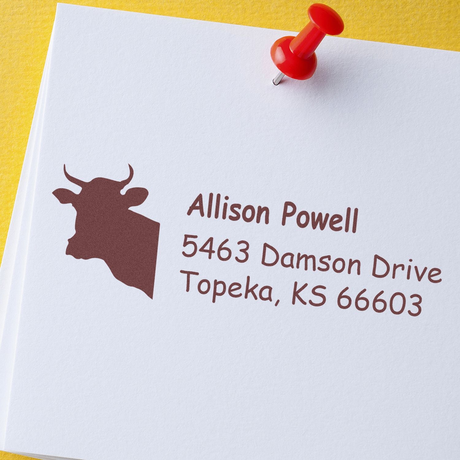 Custom rubber return address stamp with cow logo and Topeka, KS address on white paper