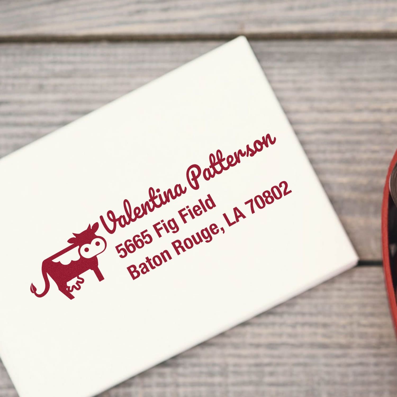 Custom rubber return address stamp with cow graphic for Valentina Patterson, Baton Rouge, LA on a white envelope.