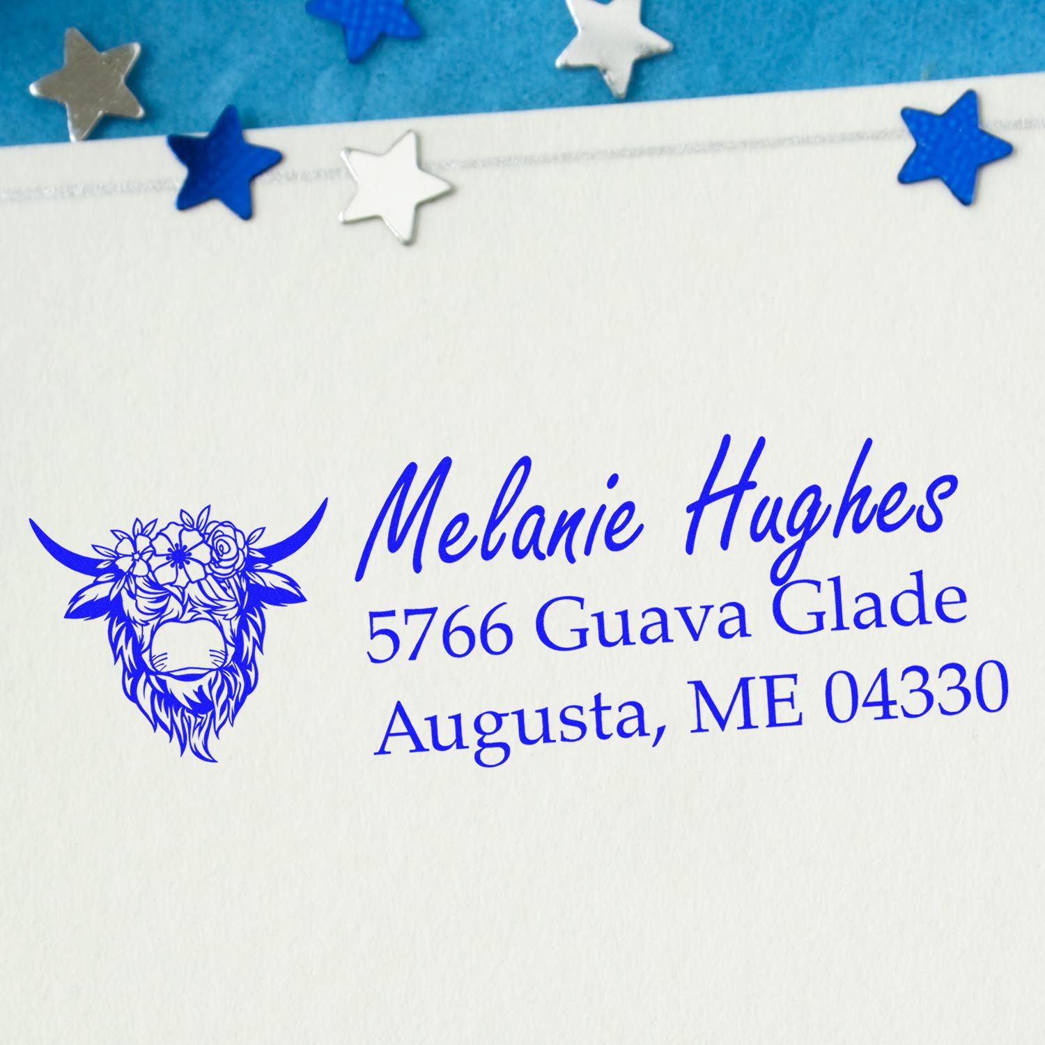 Custom cow floral address rubber stamp in blue ink on envelope, featuring Melanie Hughes return address in Augusta, ME.