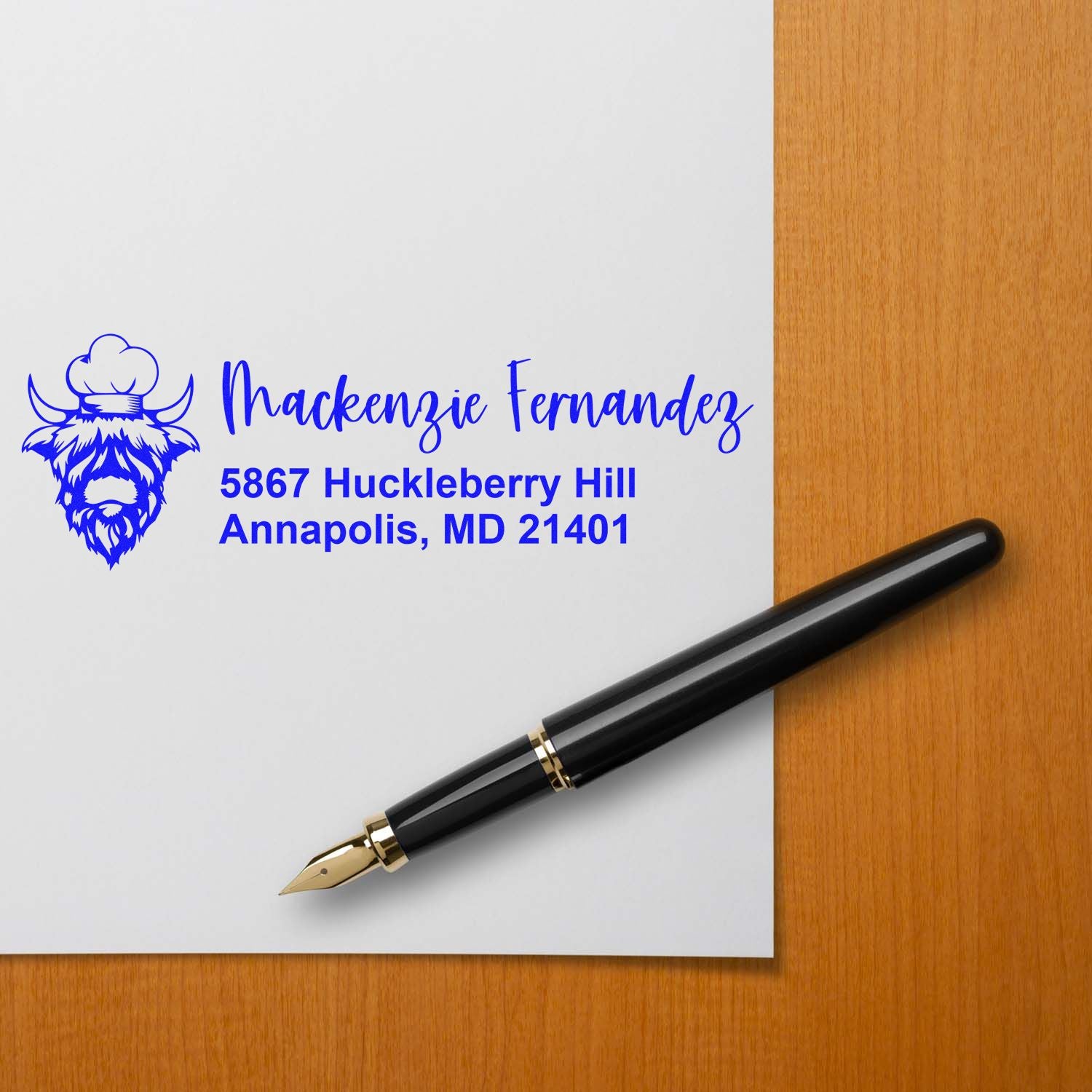 Custom Highland cow address stamp with name and Annapolis, MD return address on paper beside a fountain pen.