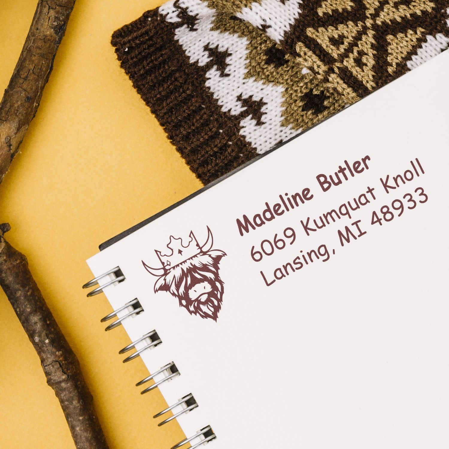 Custom return address rubber stamp with elk logo and address on a spiral notebook, ideal for personalized stationery.