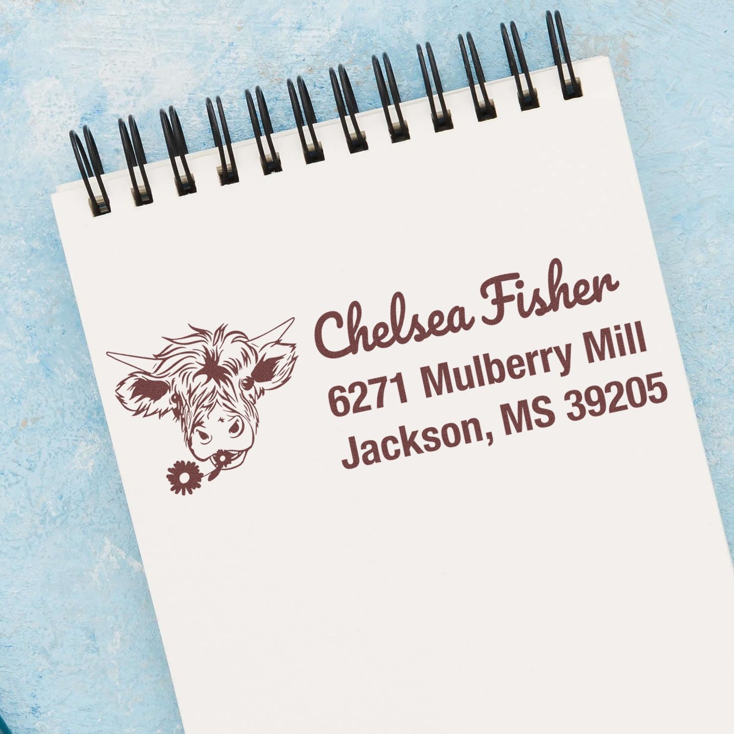 Custom cow address rubber stamp with name, street address and Jackson, MS on notepad