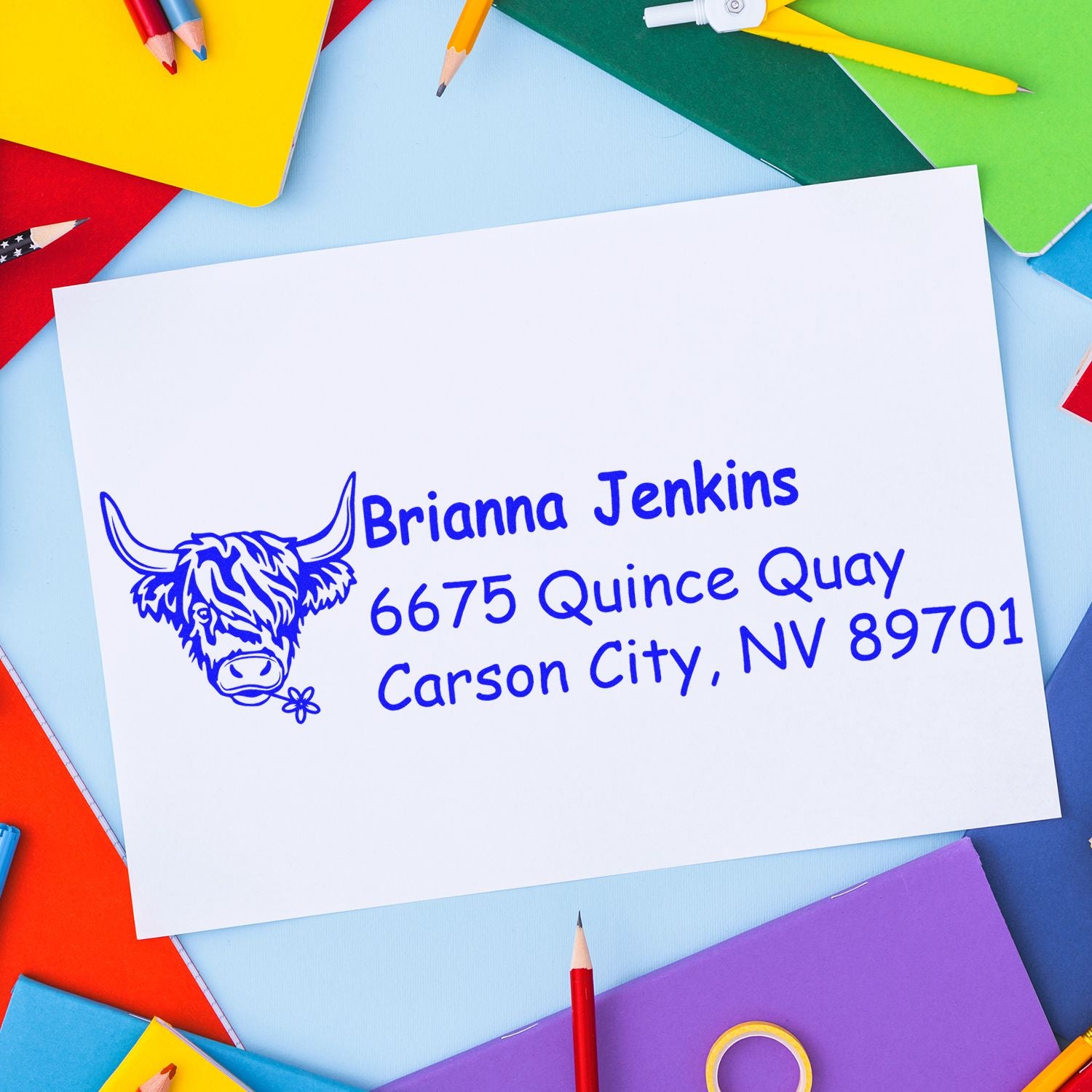 Custom return address rubber stamp with cow logo on envelope, surrounded by colorful stationery.