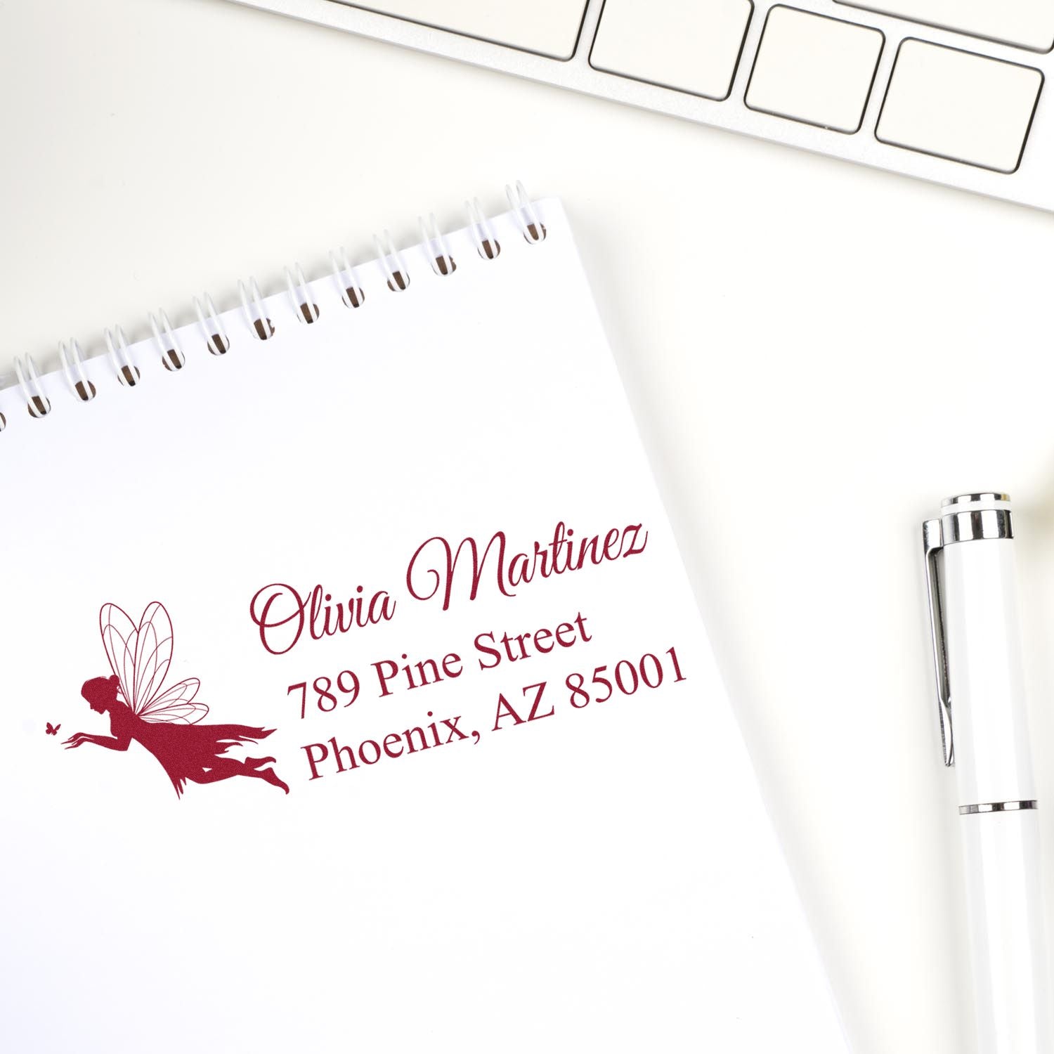 Custom return address rubber stamp with fairy silhouette, personalized for Olivia Martinez, shown on a notebook page.