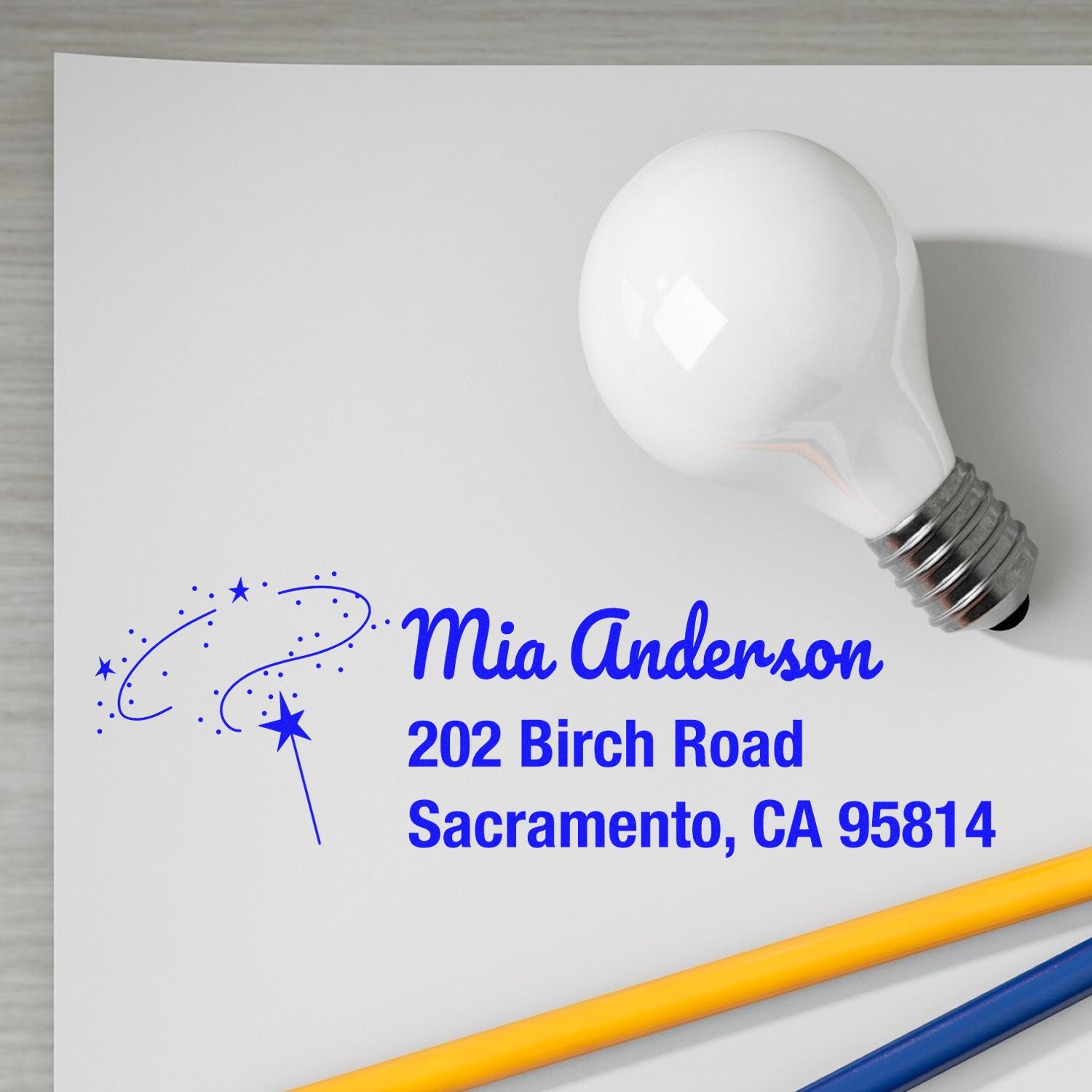 Blue ink personalized return address rubber stamp mockup with name, address, and star wand design for mailing stationery.