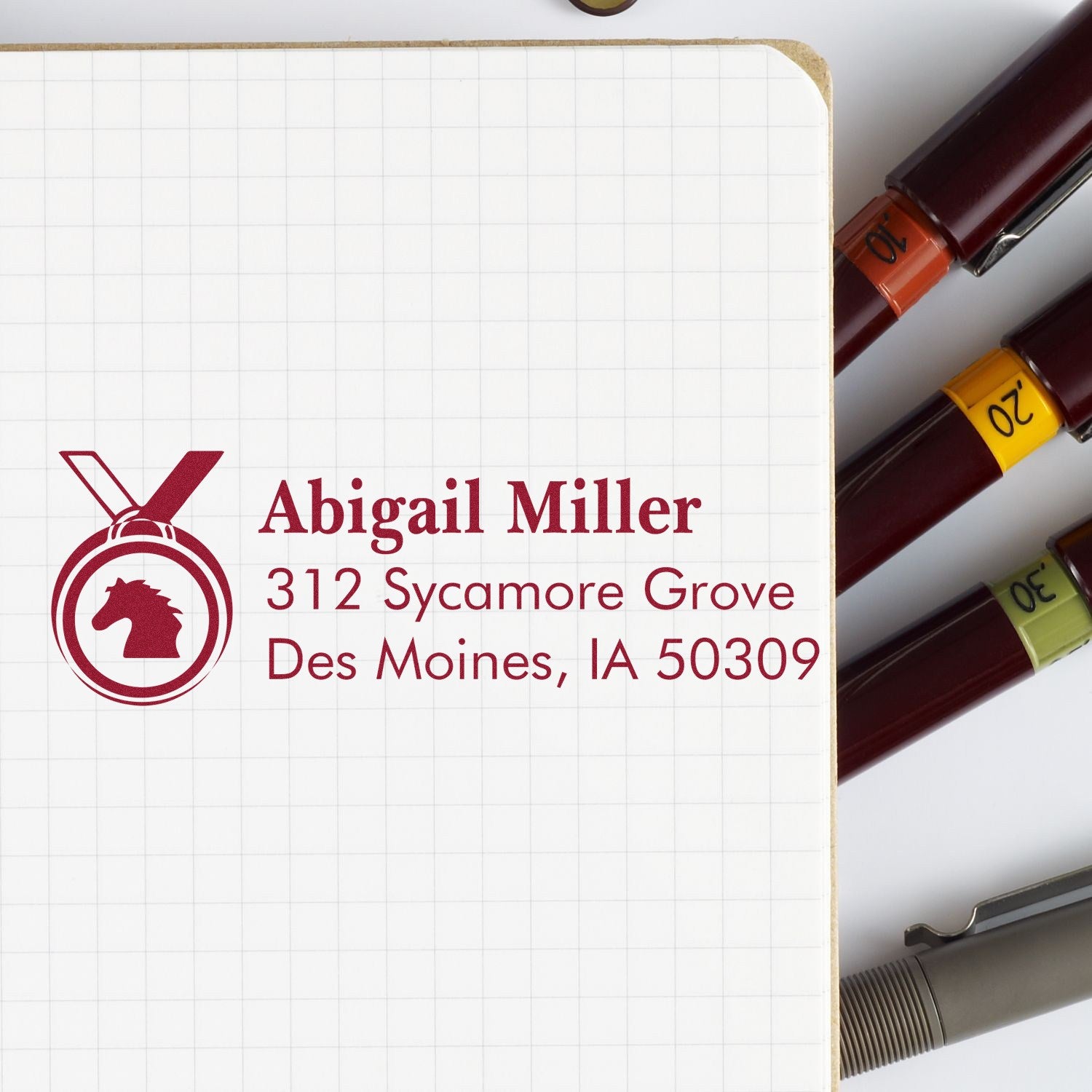 Custom rubber address stamp with horse logo for Abigail Miller, 312 Sycamore Grove, Des Moines, IA 50309.
