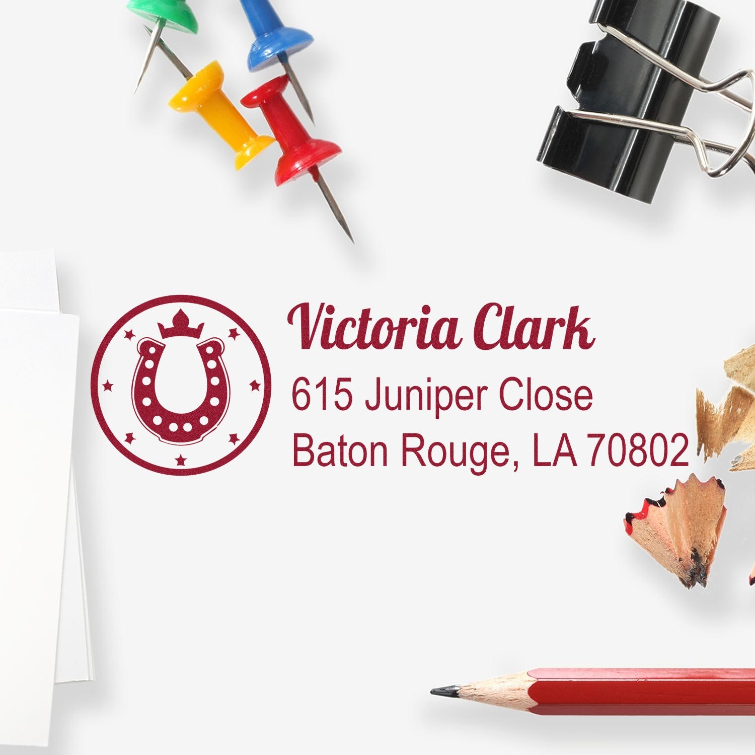Custom return address rubber stamp with horseshoe logo, Victoria Clark name, and Baton Rouge, LA address on white paper.