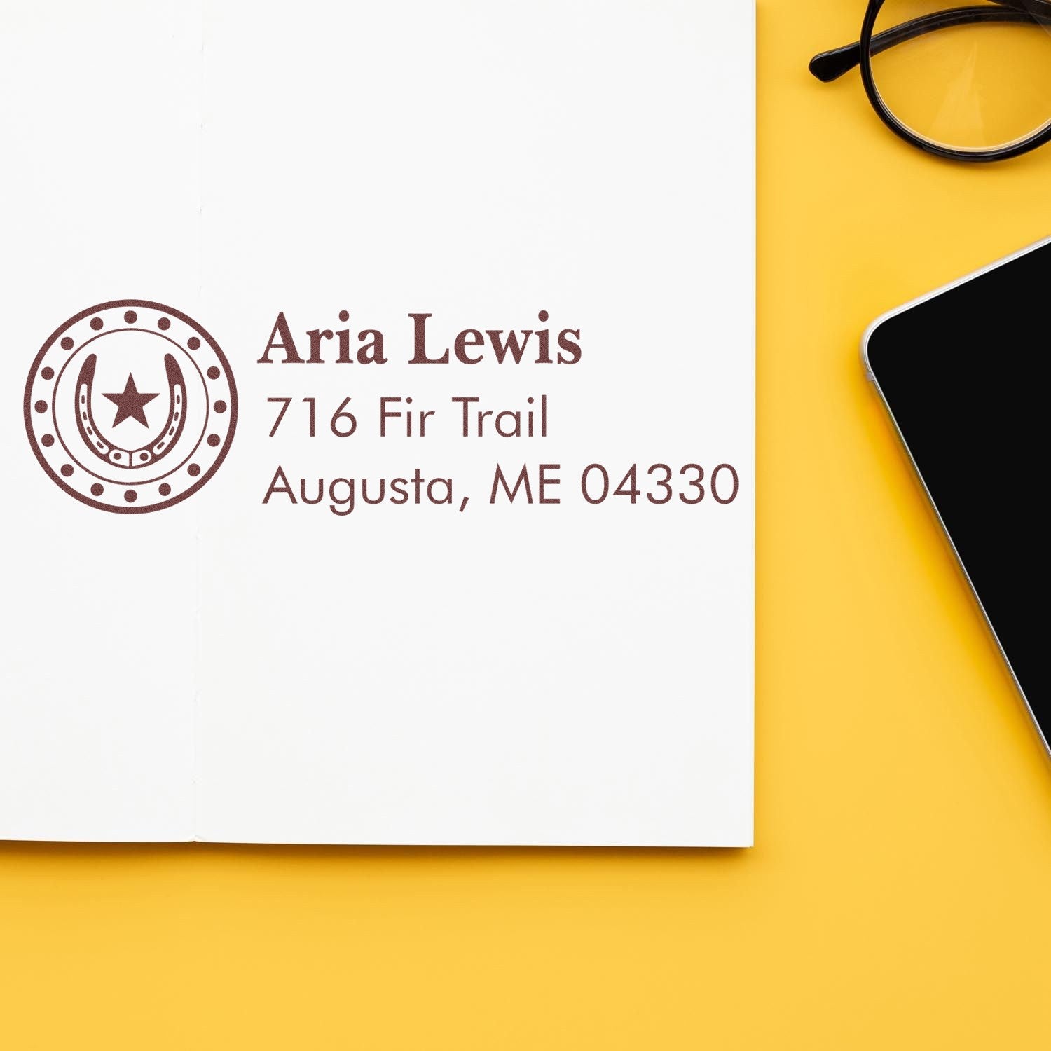 Custom return address rubber stamp imprint with name, street address, and horseshoe logo on notebook paper.