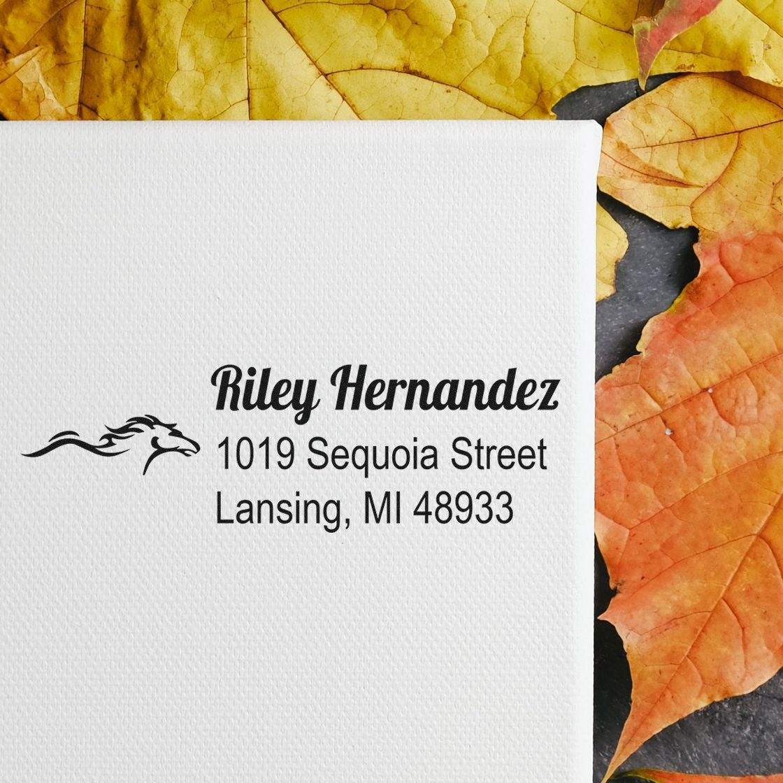 Personalized return address rubber stamp for Riley Hernandez with horse logo, Lansing MI address on white paper.