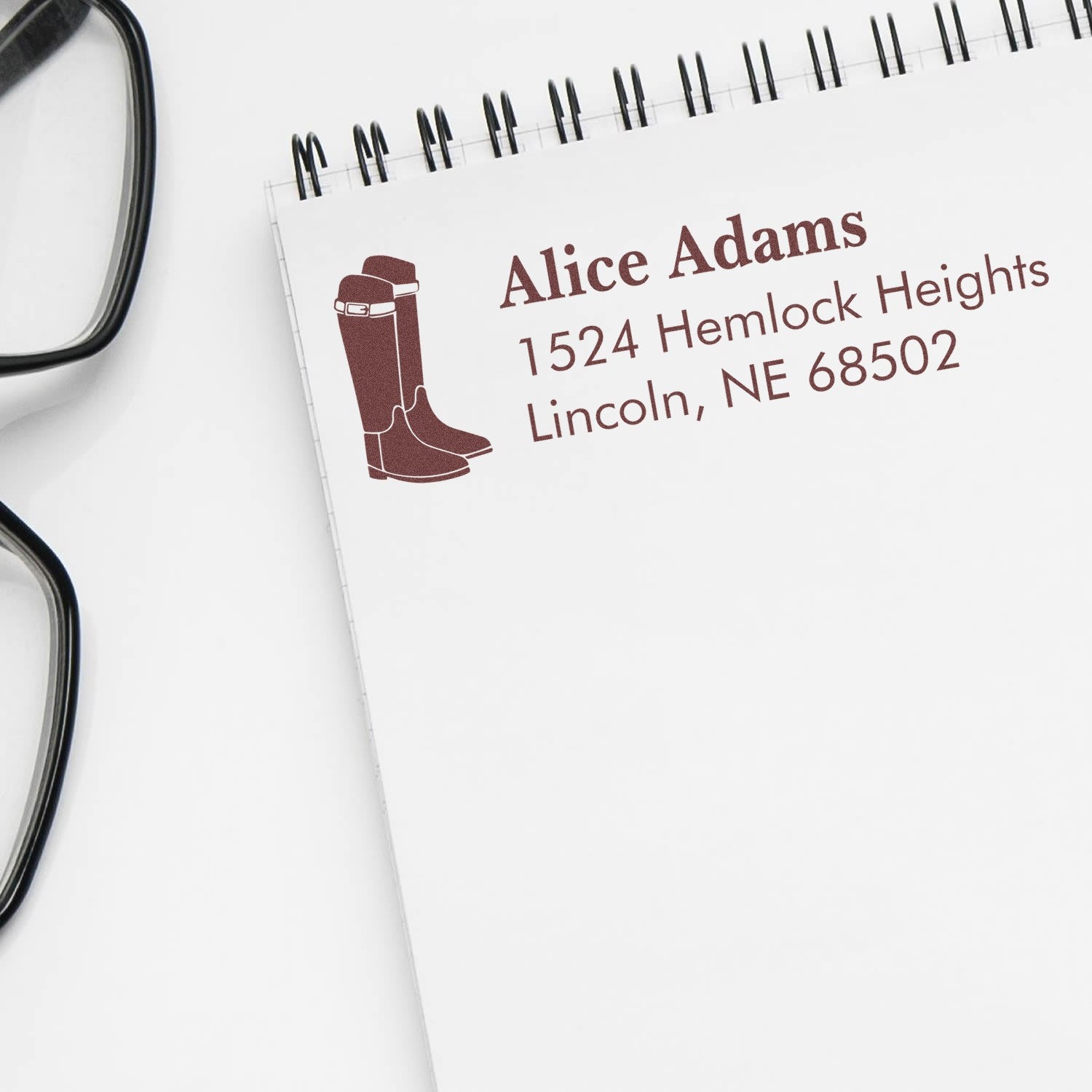Custom return address rubber stamp with cowboy boots icon, name, and Lincoln, NE address on notebook.