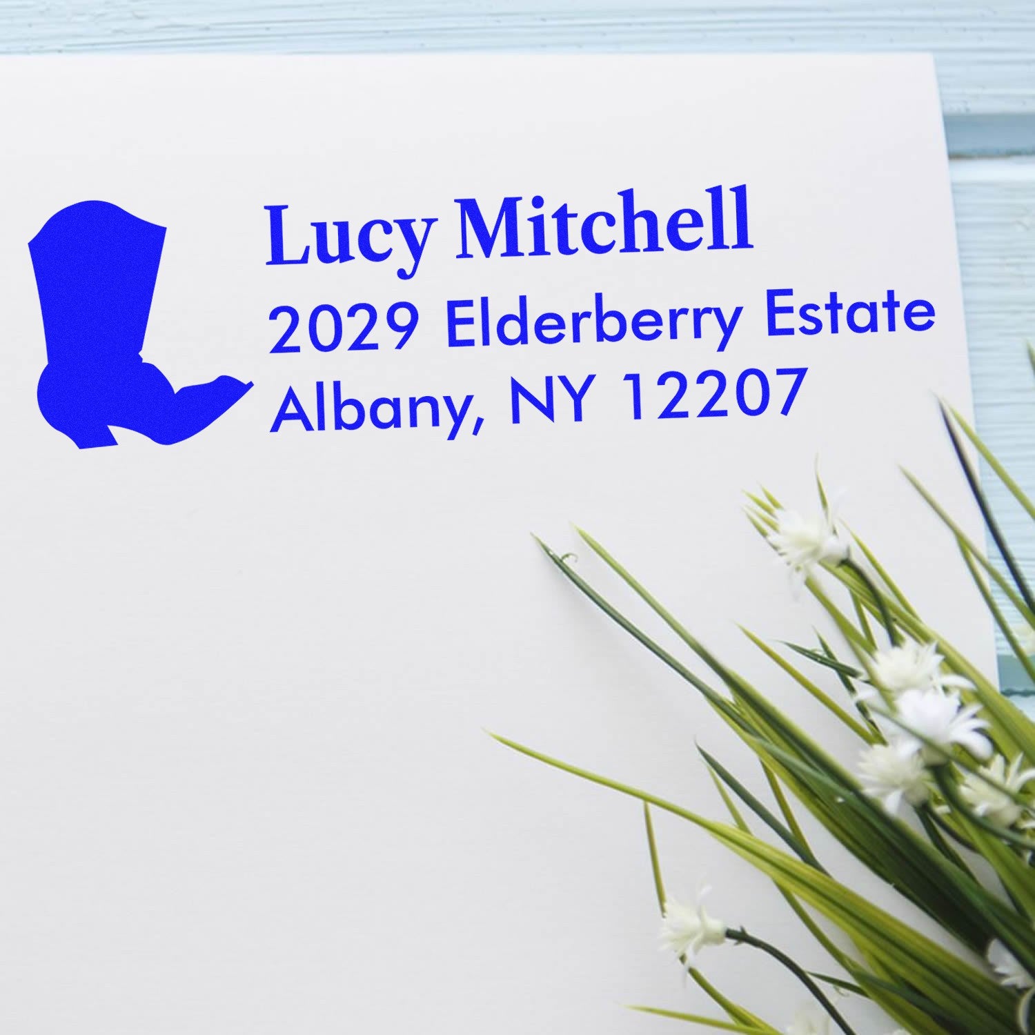 Personalized return address rubber stamp for Lucy Mitchell, 2029 Elderberry Estate, Albany, NY 12207 on a white envelope.
