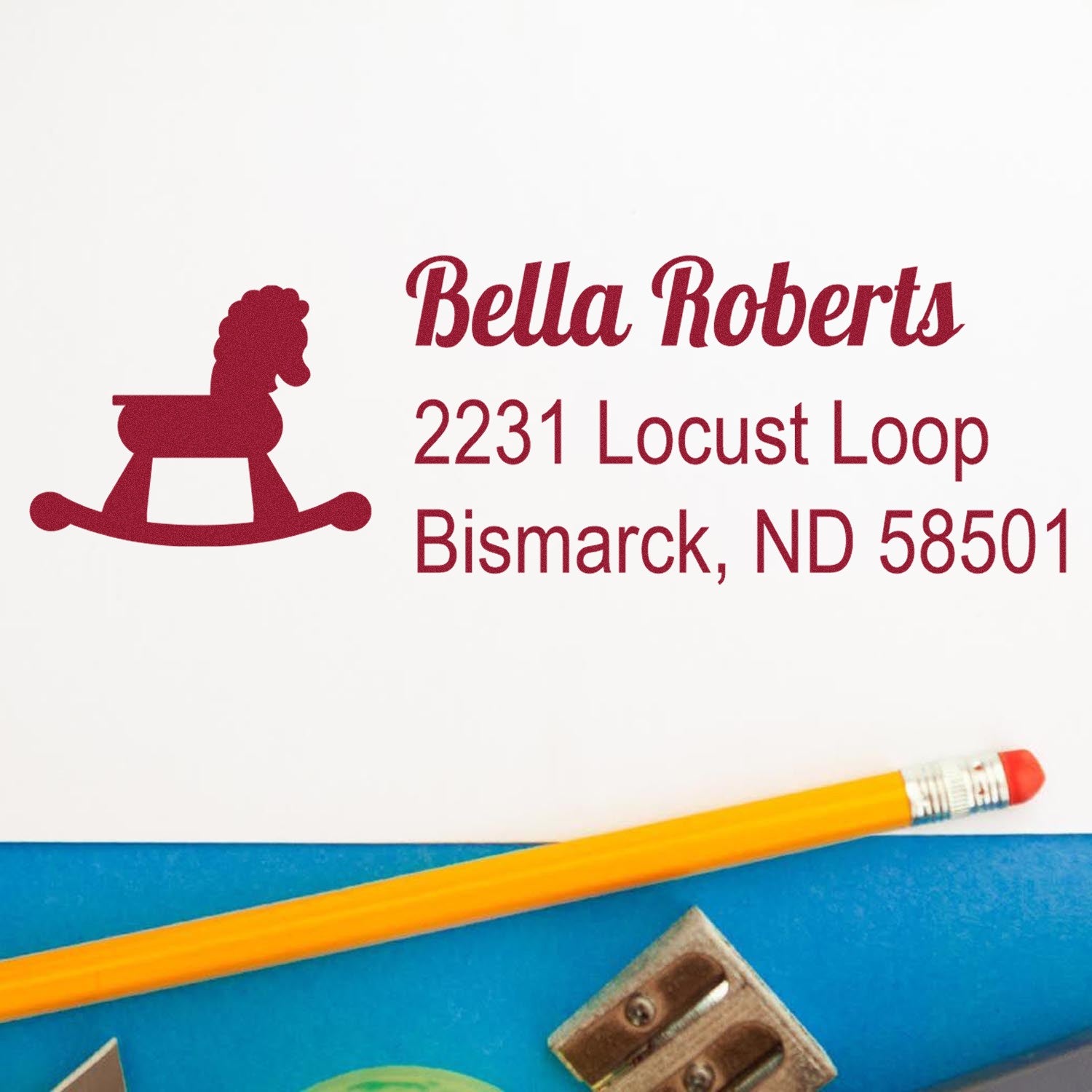 Custom rubber address stamp with rocking horse design and Bella Roberts, 2231 Locust Loop, Bismarck, ND 58501.