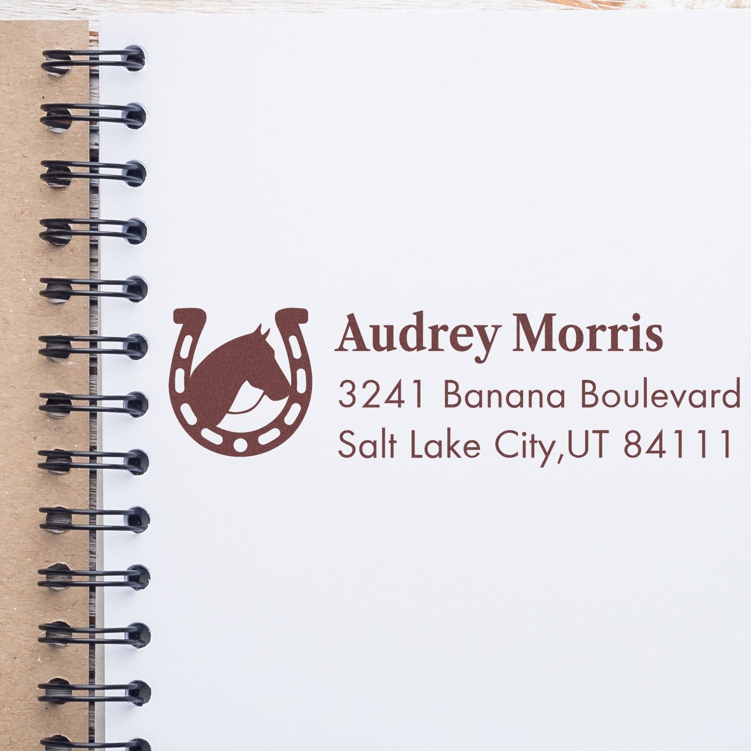 Personalized horse rubber stamp with horseshoe logo, Audrey Morris name and address on a notebook page.
