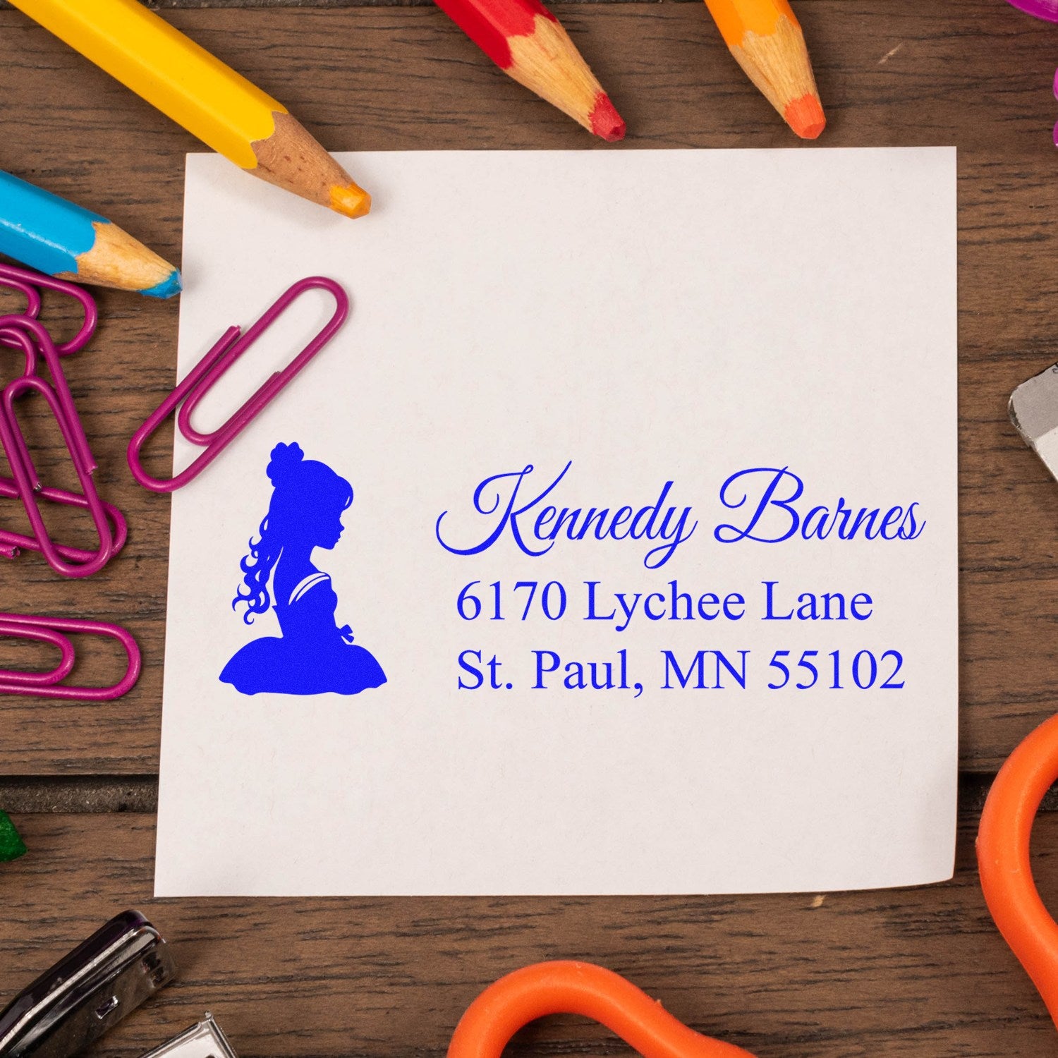 Custom rubber address stamp with girl silhouette and blue return address imprint on white stationery.