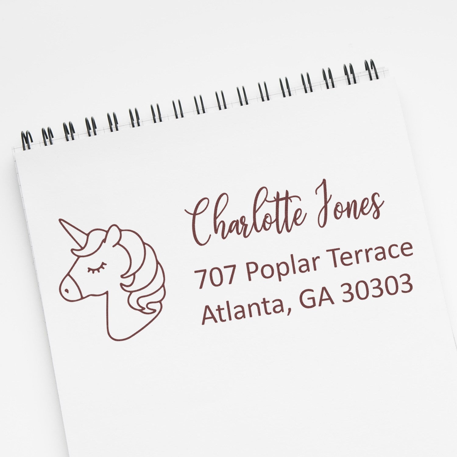 Personalized unicorn address rubber stamp with name and Atlanta, GA return address on a notebook page