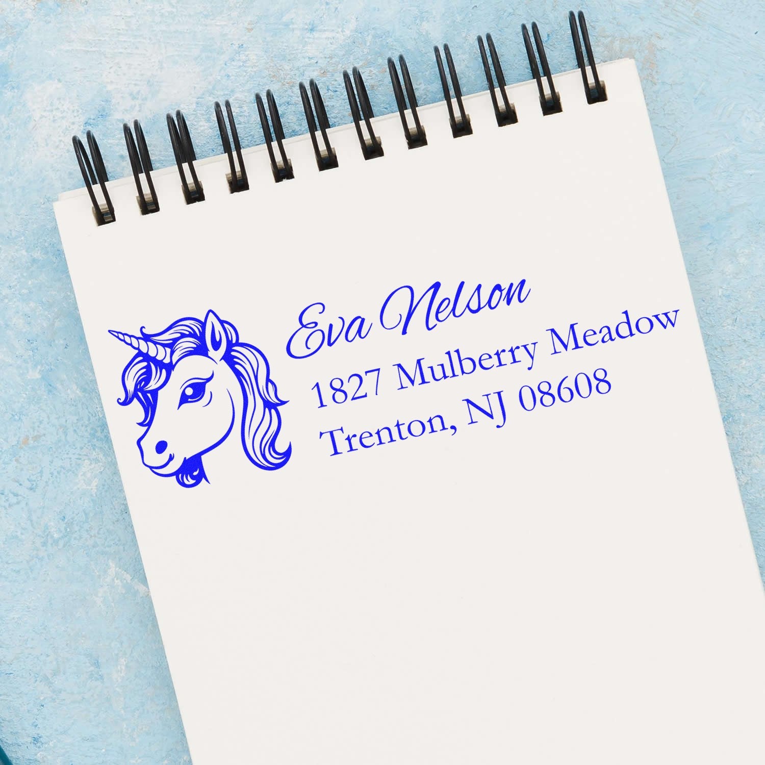 Personalized unicorn address rubber stamp with name and Trenton, NJ address on notebook page.