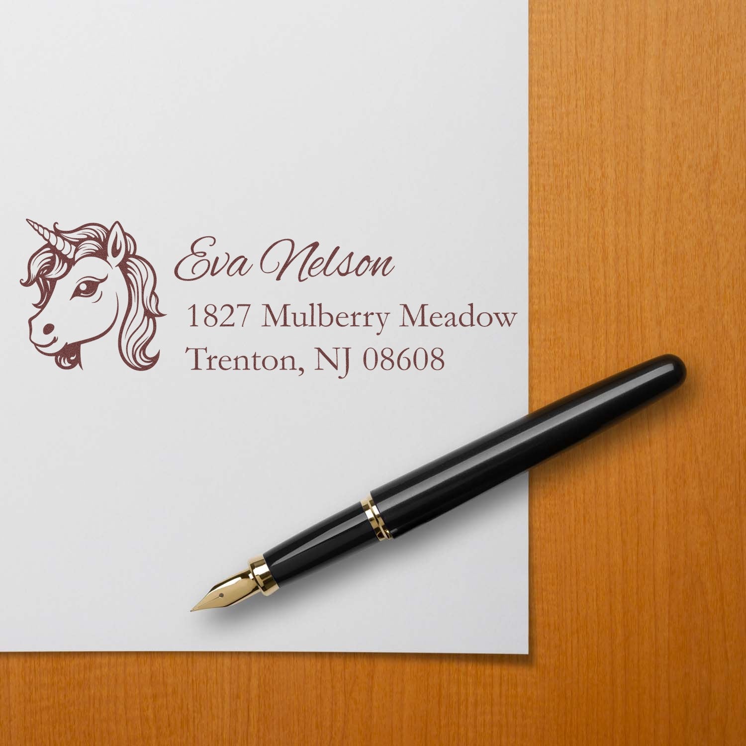 Custom unicorn rubber stamp with return address for personalized stationery, shown with fountain pen on white paper.