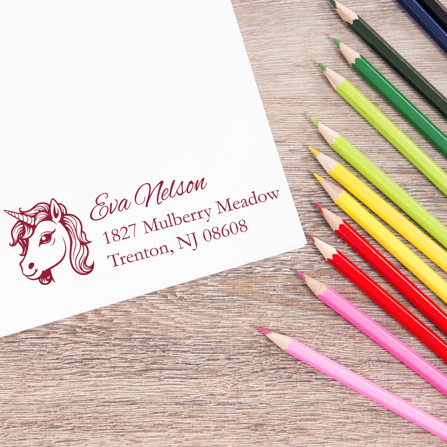 Custom unicorn rubber stamp with personalized return address for stationery, cards, and crafts beside colored pencils