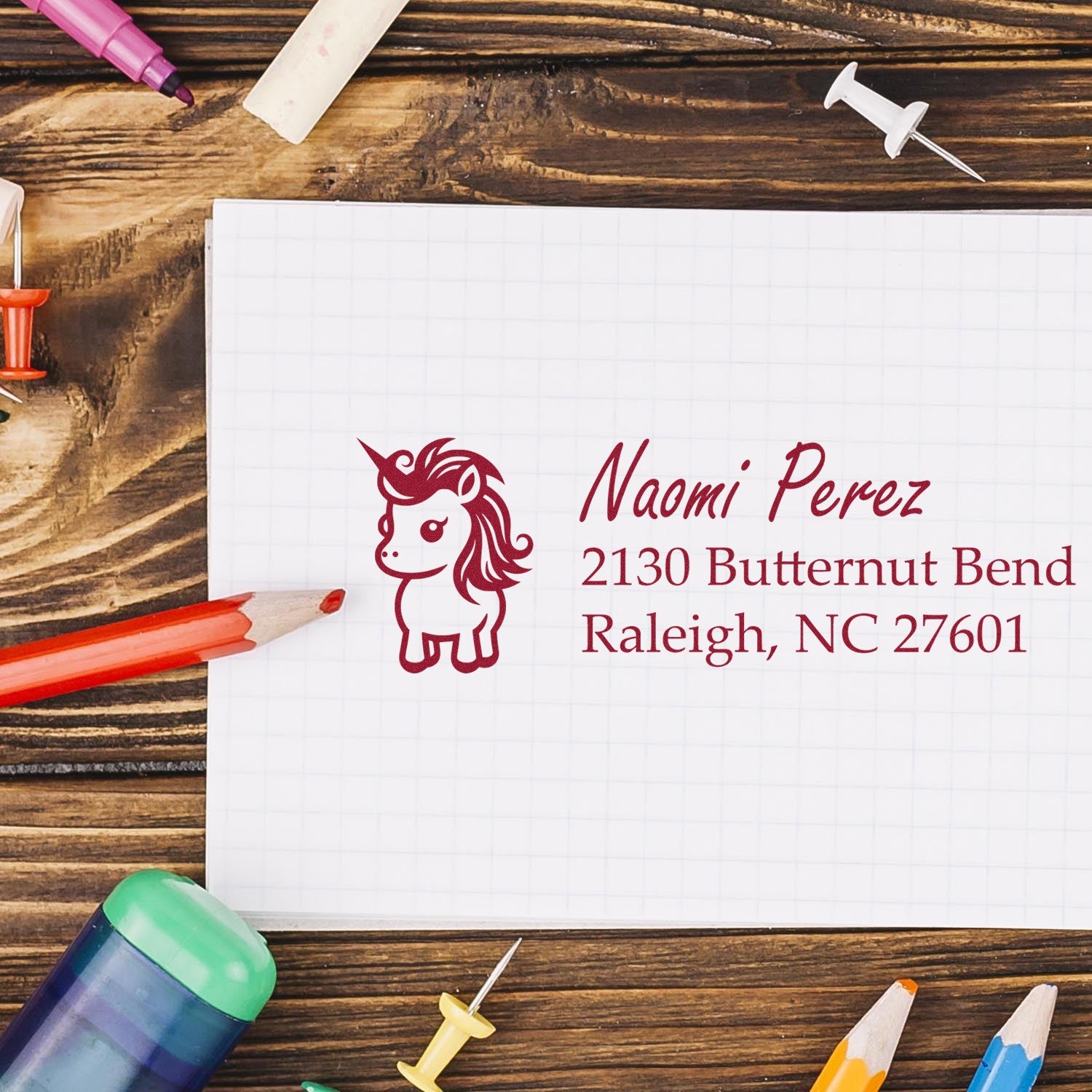 Custom unicorn address rubber stamp with name and mailing address on a notebook page, ideal for personalized stationery and crafts.
