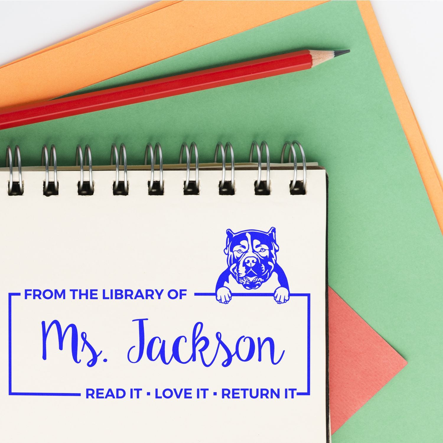 Personalized library rubber stamp for Ms. Jackson with dog design and Read it, love it, return it message on a notebook.