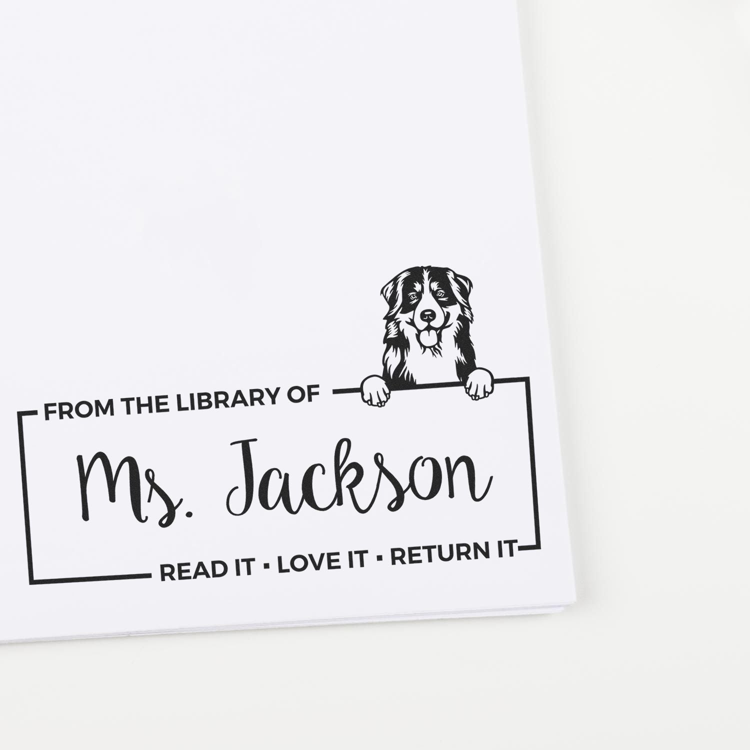 Personalized dog library rubber stamp reading From the Library of Ms. Jackson for book ownership and return reminders.