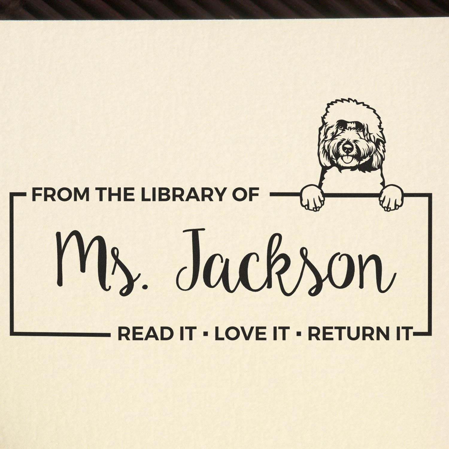 Personalized library rubber stamp for Ms. Jackson with dog illustration and Read It, Love It, Return It bookplate text.