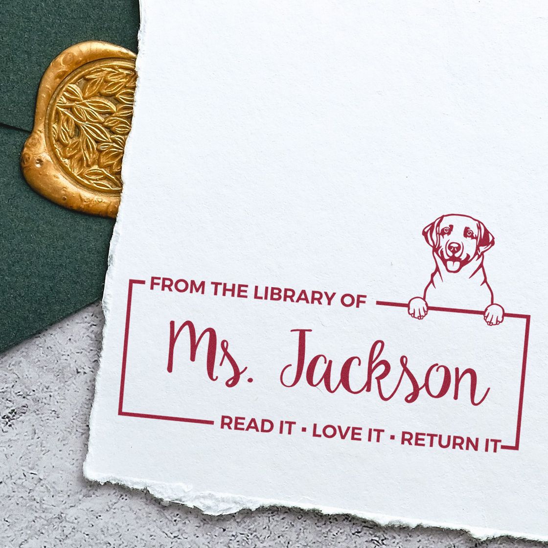 Personalized library rubber stamp for Ms. Jackson with dog graphic and Read it, Love it, Return it book label.