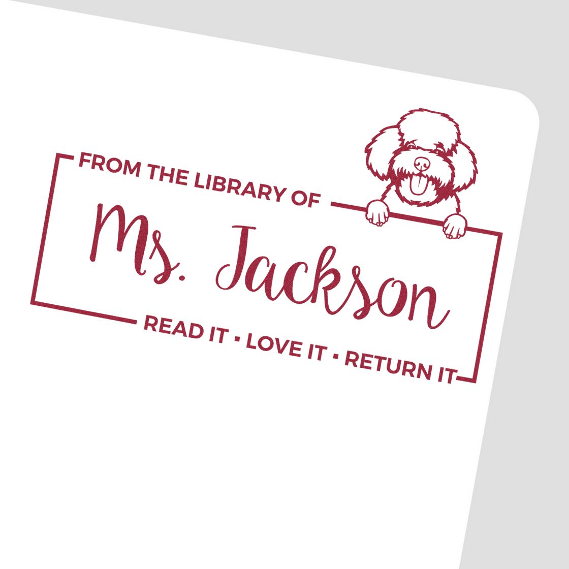 Personalized library rubber stamp with dog illustration, featuring From the Library of Ms. Jackson and read-it-love-it-return-it text.