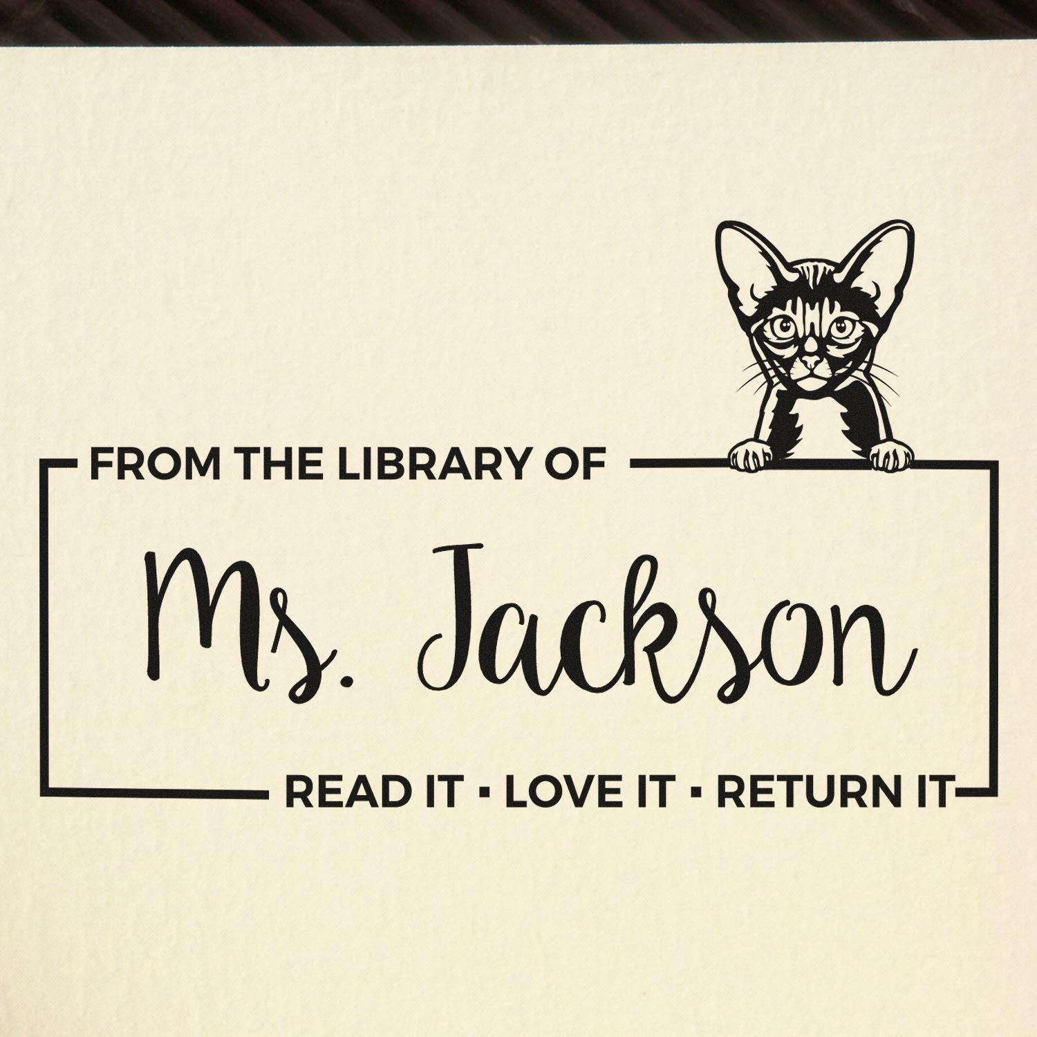 Custom rubber stamp with cat illustration and personalized library bookplate text: From the Library of Ms. JacksonRead it, love it, return it.