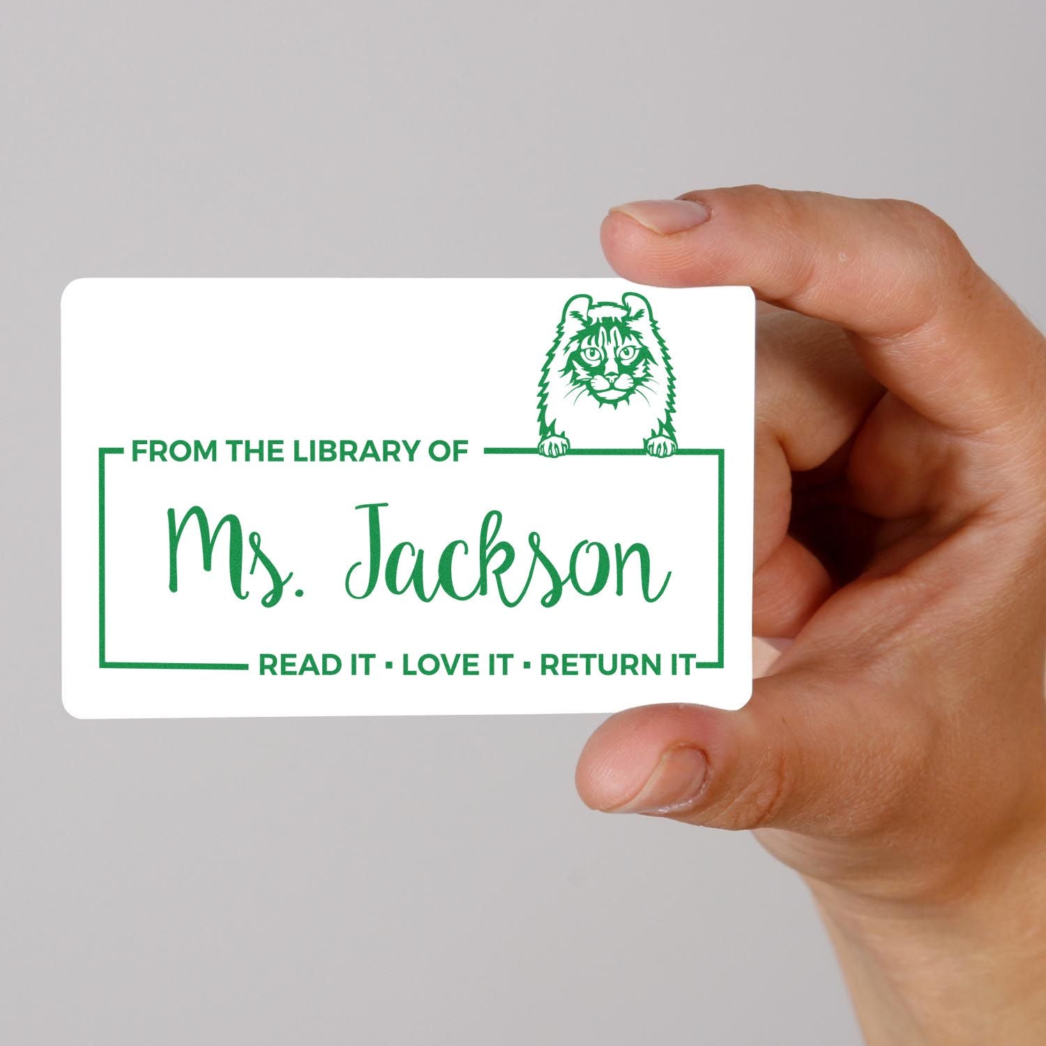 Hand holding custom library rubber stamp for Ms. Jackson with tiger design and Read it, Love it, Return it message.