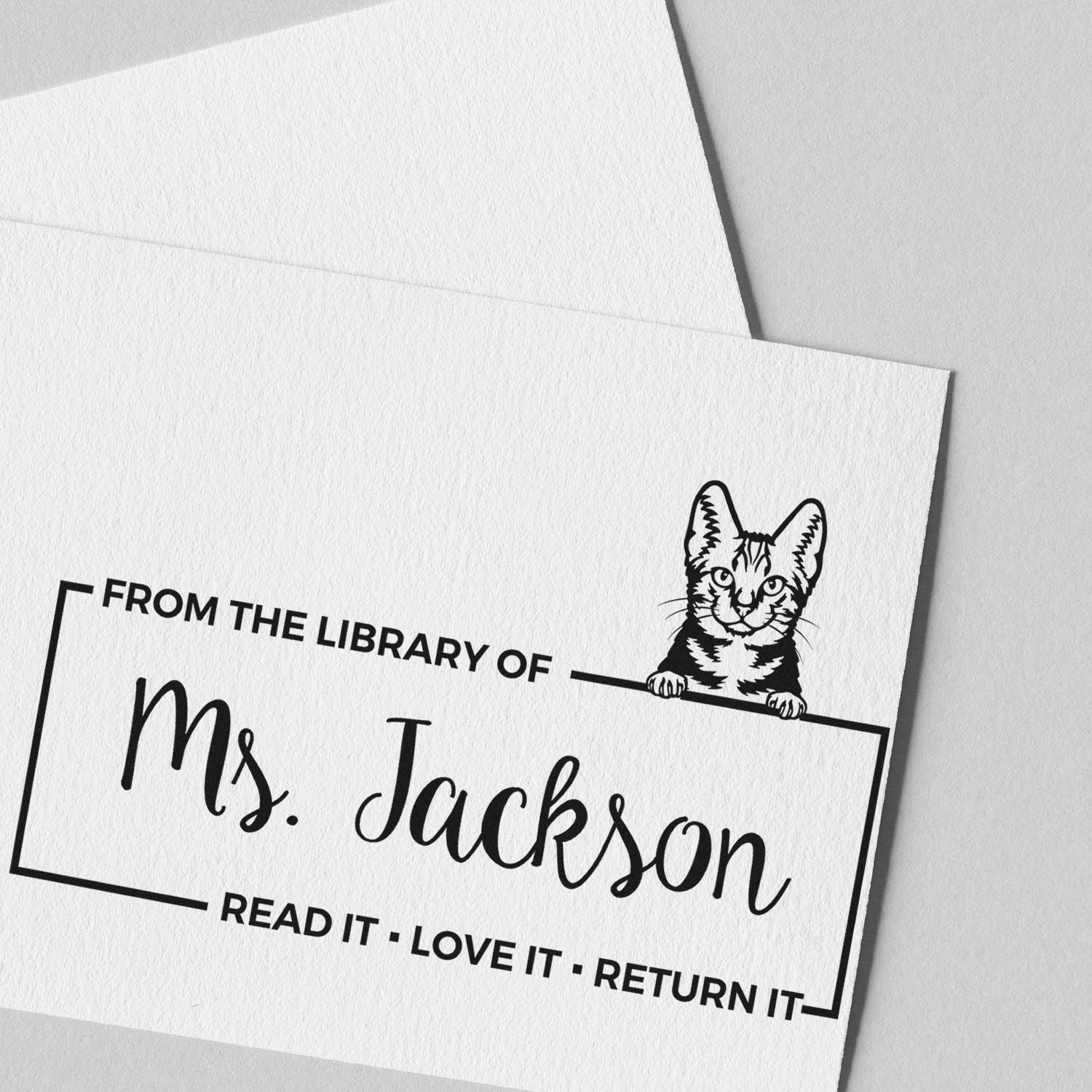 Personalized library rubber stamp for Ms. Jackson with cat bookplate design and Read it, Love it, Return it text.
