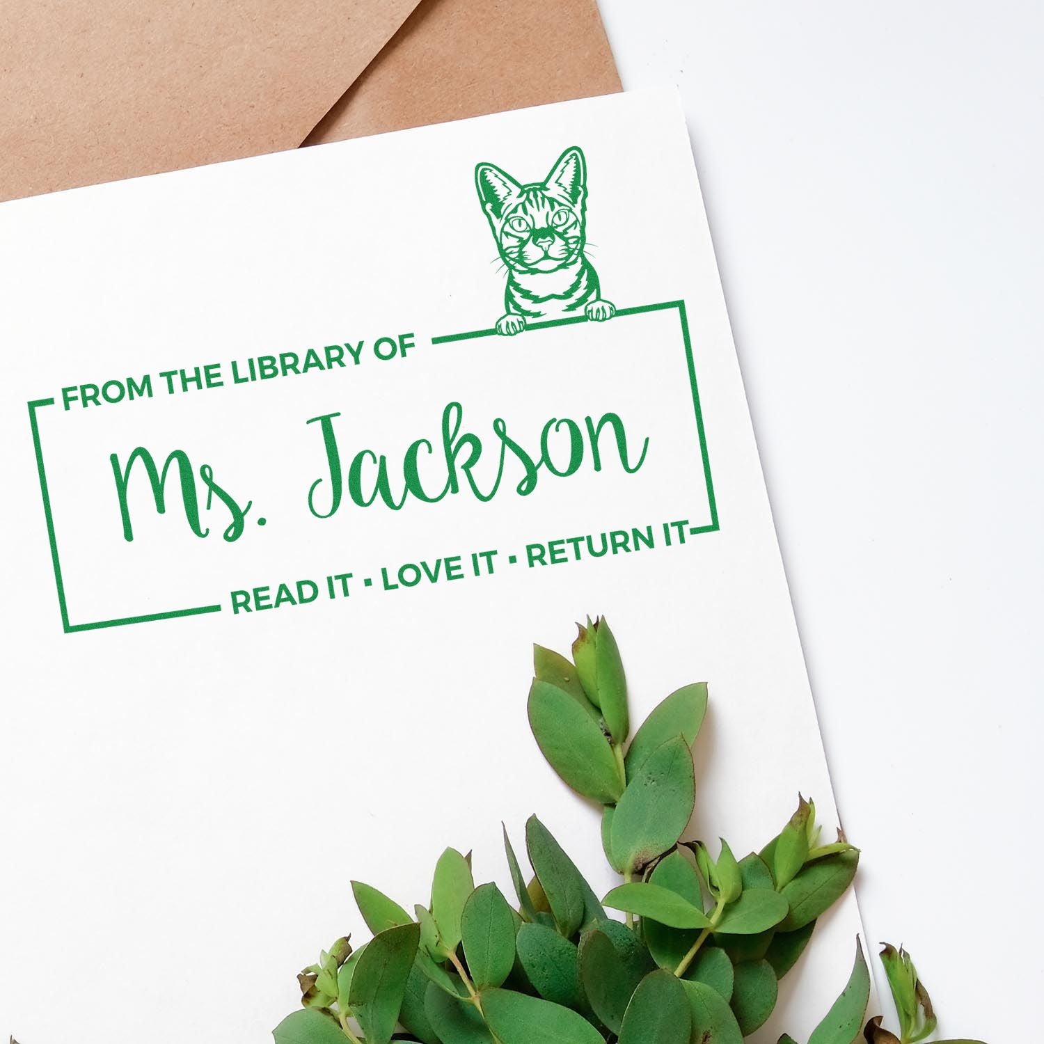 Personalized library rubber stamp with cat illustration and From the Library of Ms. Jackson read-it-love-it-return-it text.