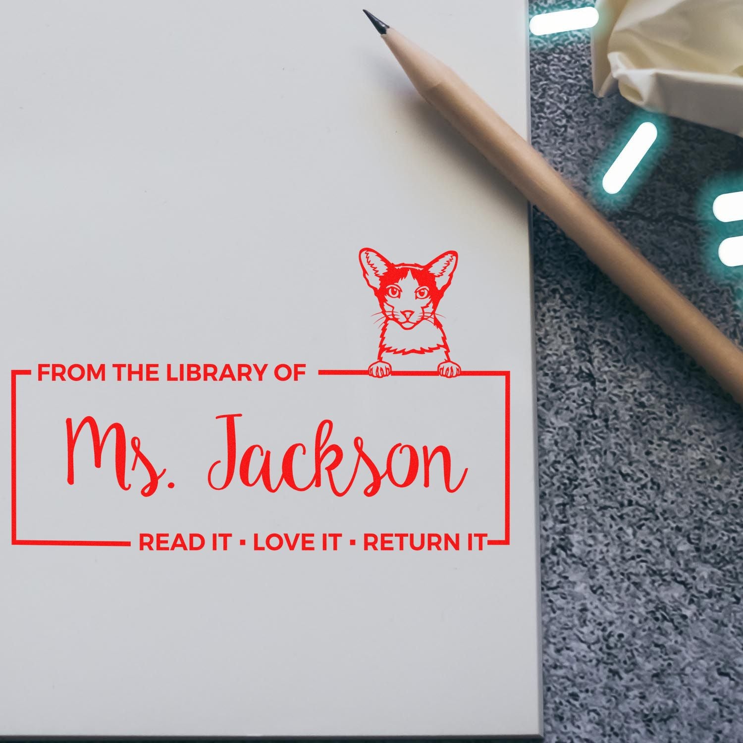 Personalized rubber library stamp for books, reading From the Library of Ms. Jackson with cat design and return reminder.